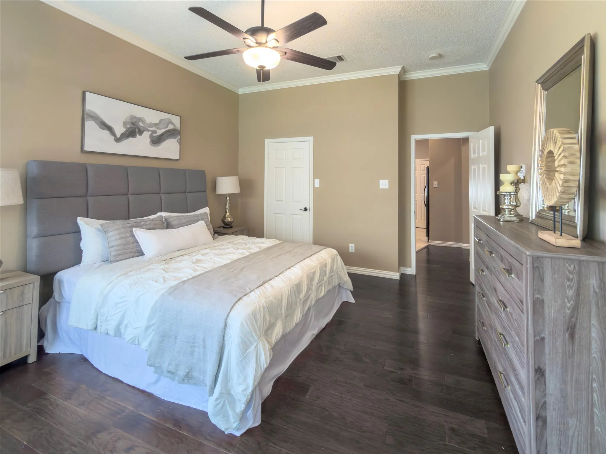 Vaulted ceiling with crown molding, ceiling fan with integrated lighting, wood-finish flooring, white paneled doors, and neutral wall tones