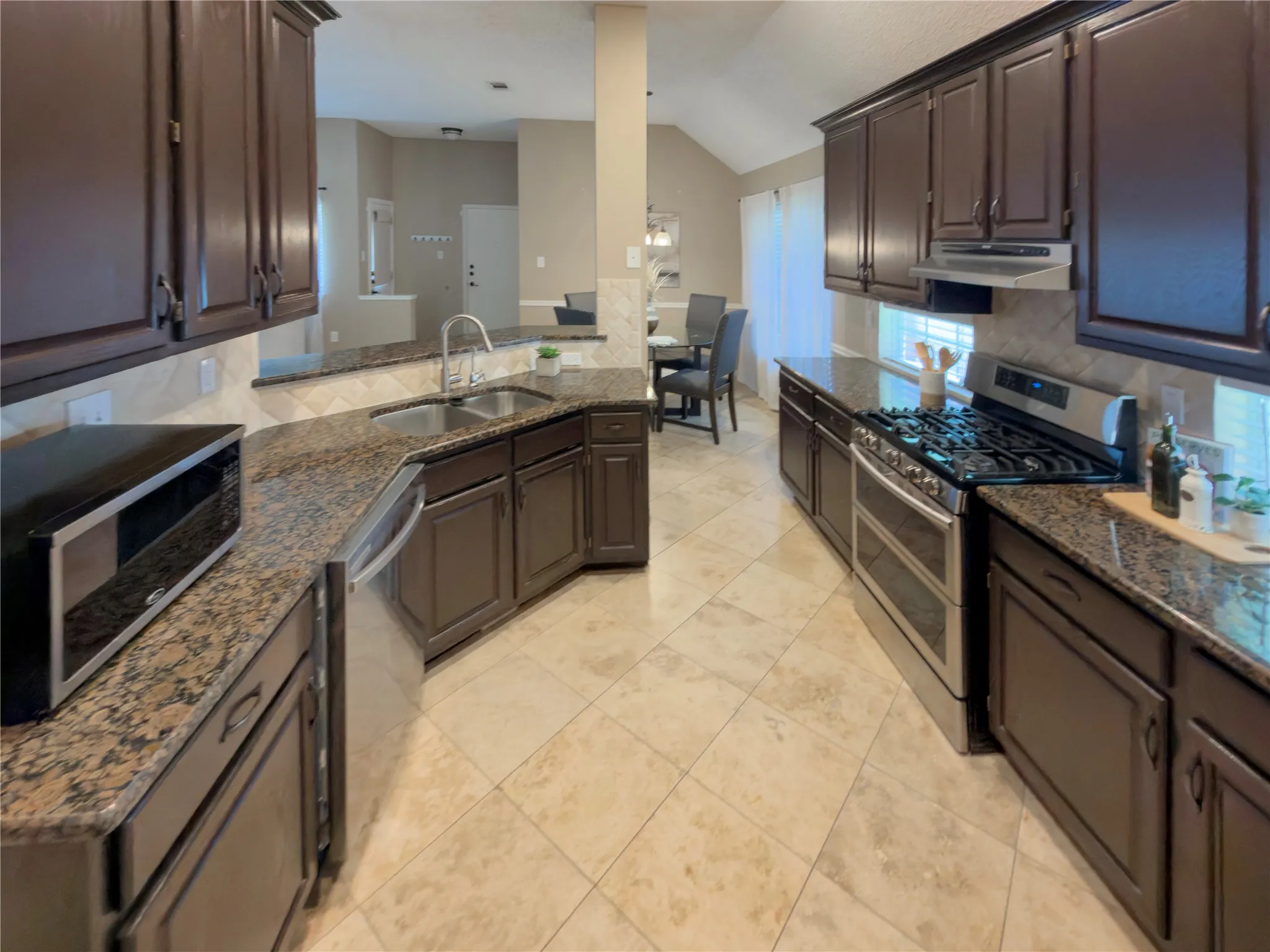 Kitchen featuring dark wood cabinetry, light-toned tile flooring, and granite countertops