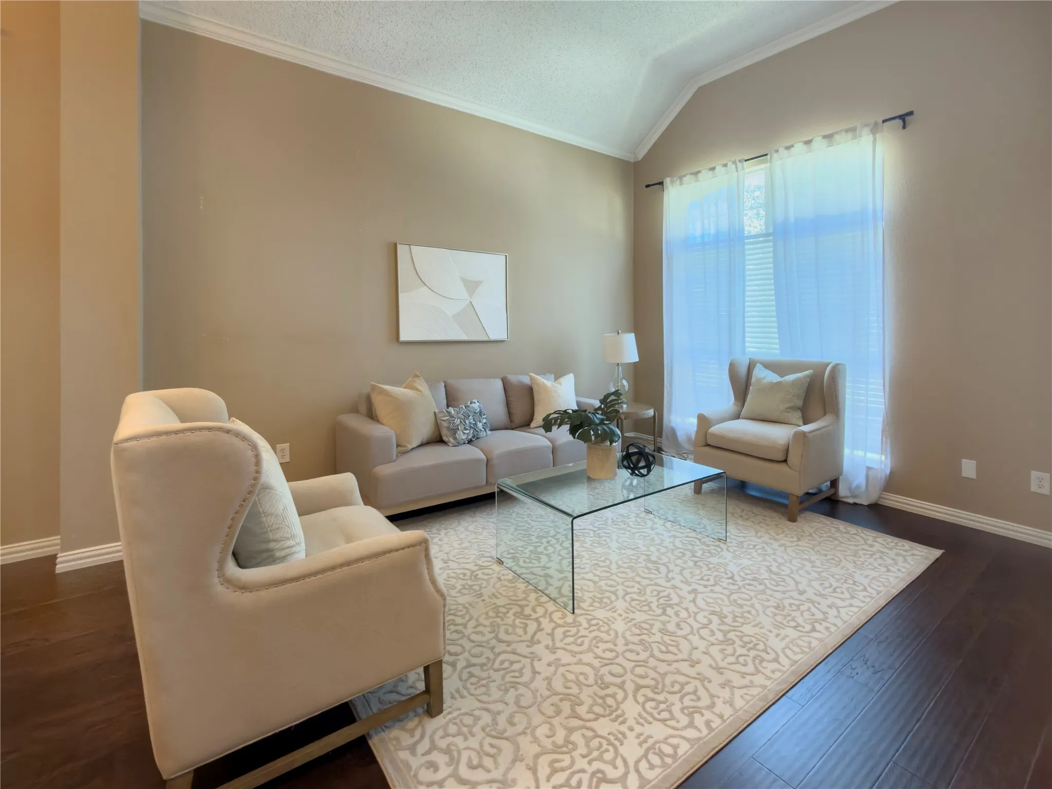 Vaulted ceiling, dark wood-finish flooring, crown molding, large window with blinds and sheer curtains, and light neutral wall colors