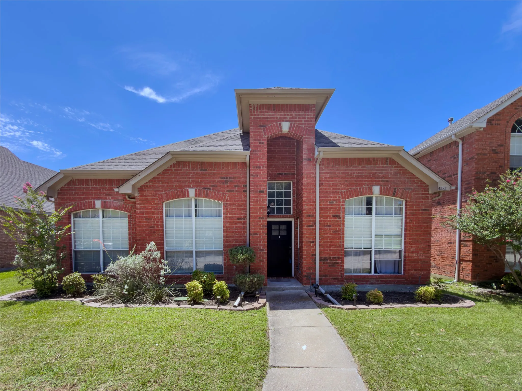 Brick facade featuring an arched entryway and dark-toned front door