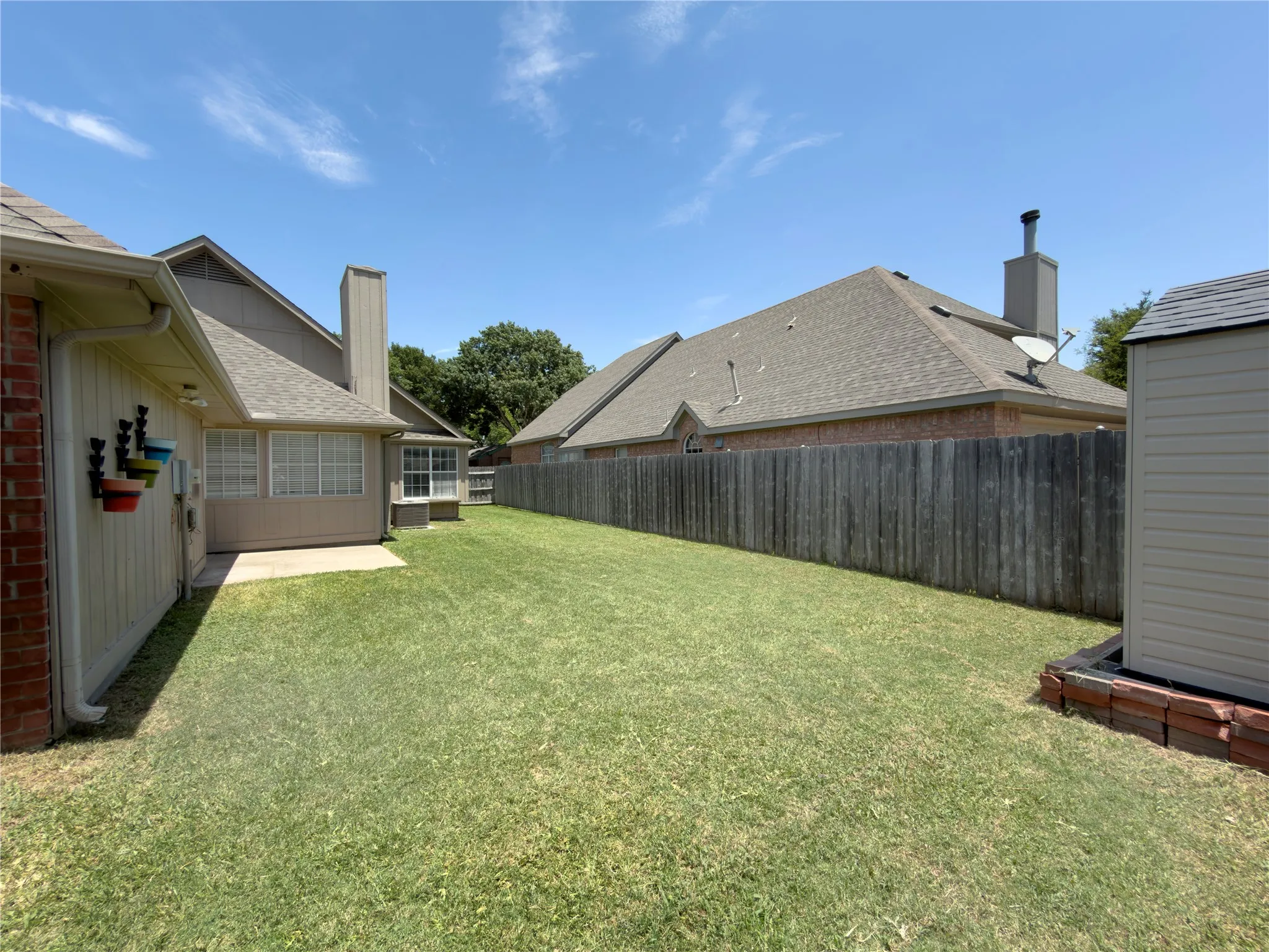 Expansive backyard featuring a manicured lawn, concrete patio, and a wood privacy fence