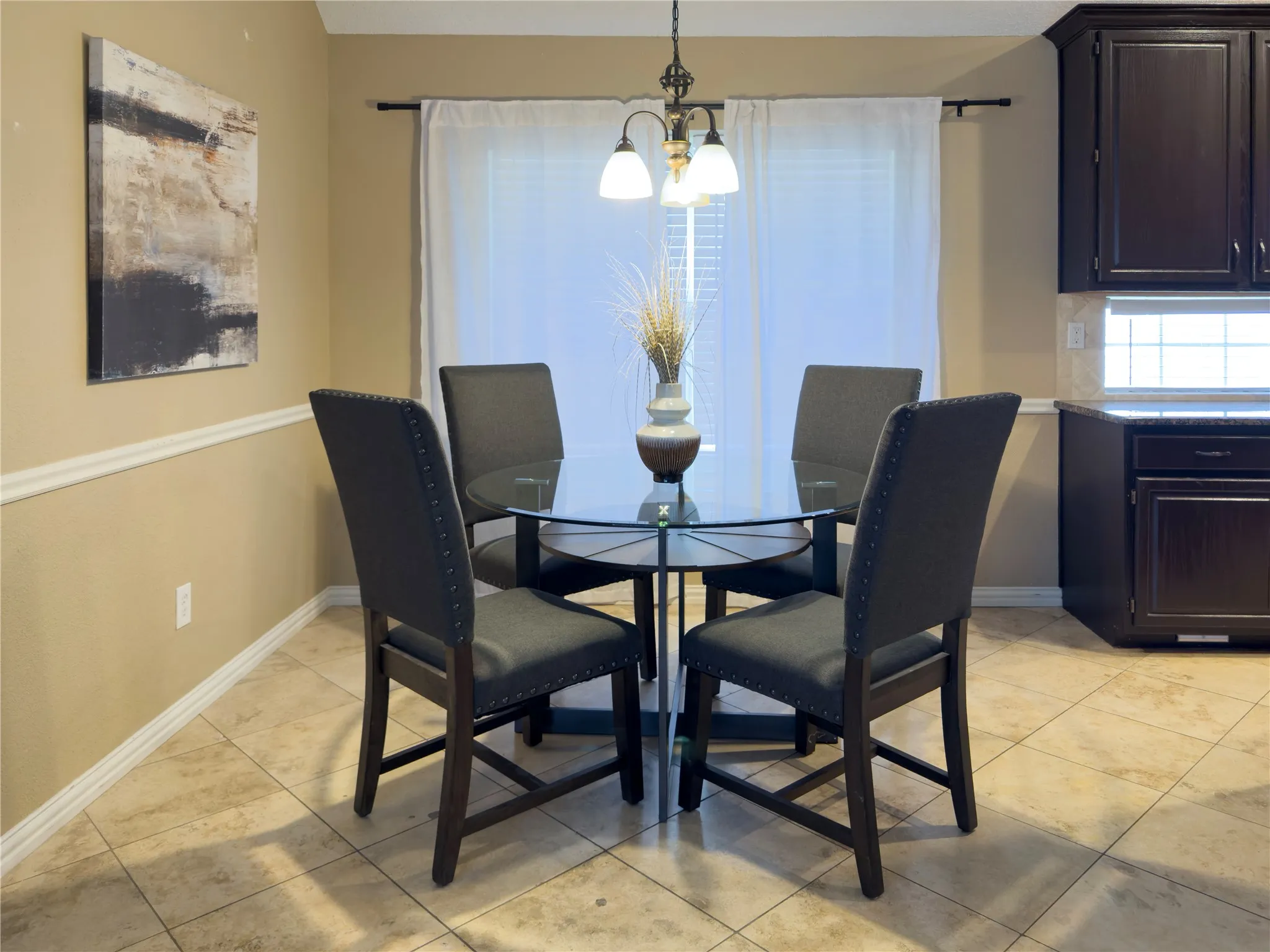 Tiled flooring with neutral tones, chair rail molding, and dark wood-finish cabinetry