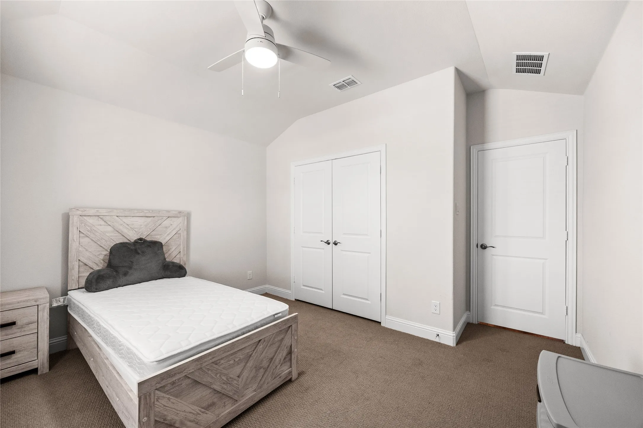 Angled ceiling with a ceiling fan, carpeted flooring, and two paneled doors
