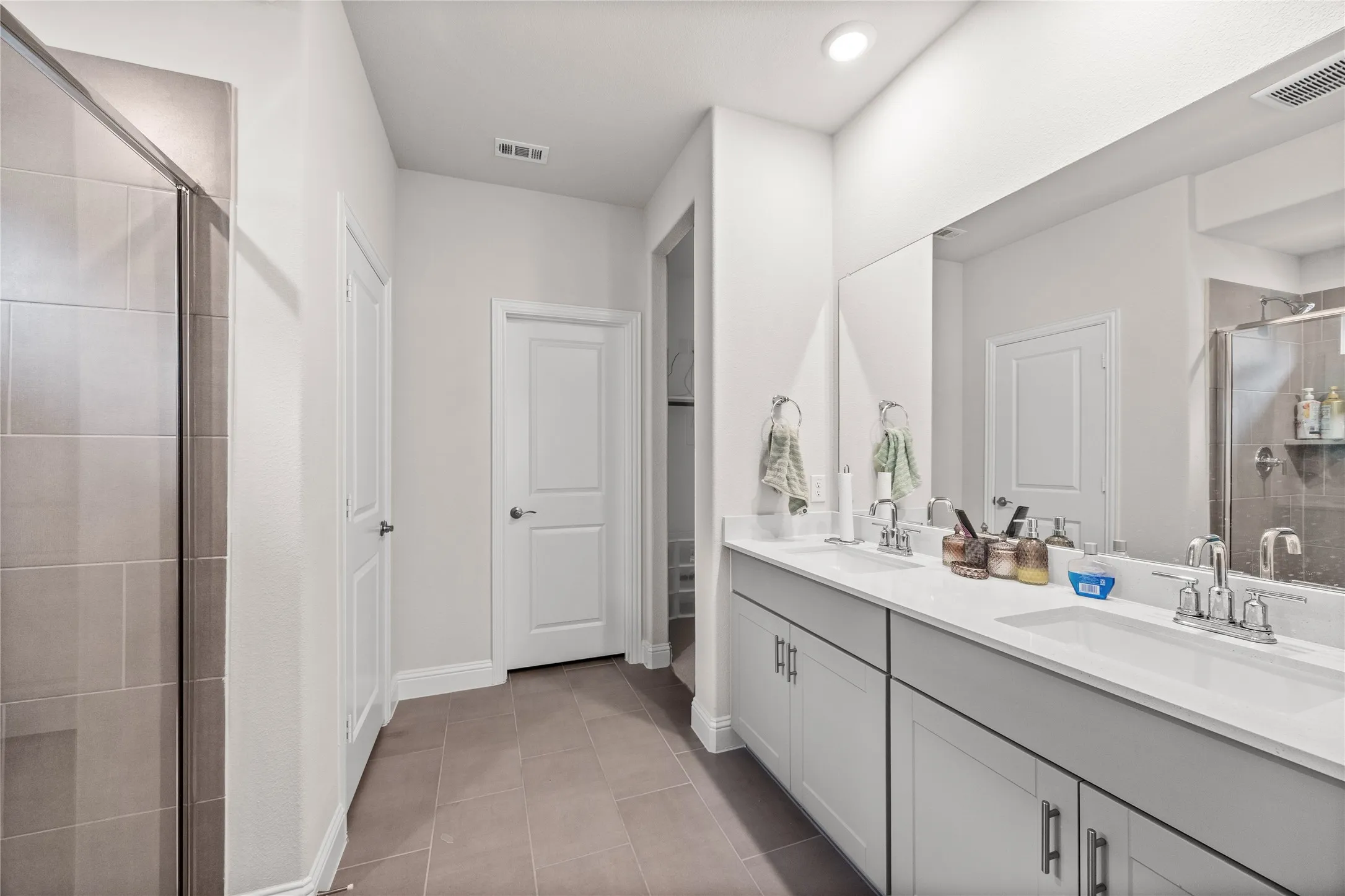 Dual vanity with white countertops, light gray cabinetry, and chrome fixtures