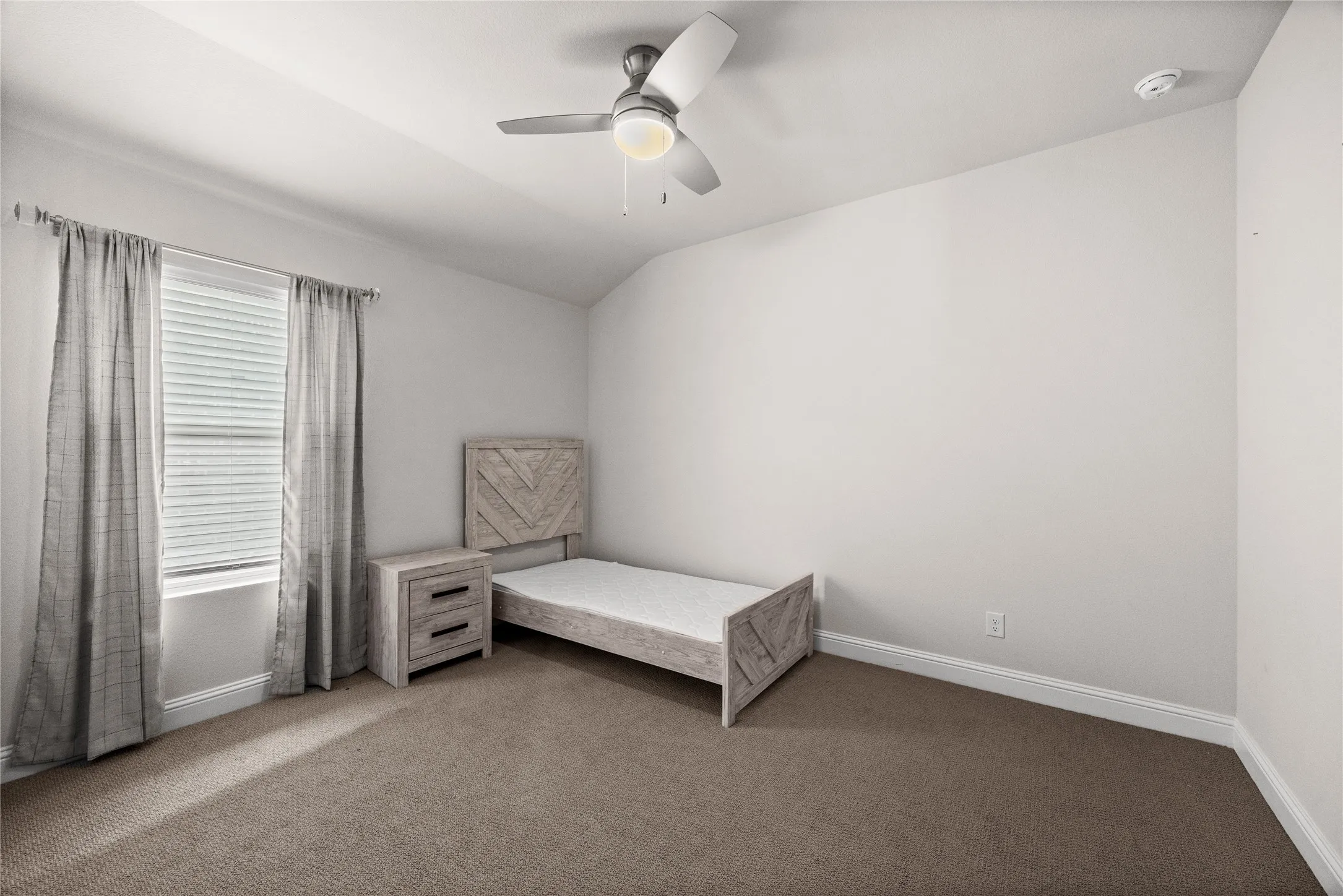 Vaulted ceiling with a ceiling fan light fixture, window with blinds, and neutral carpeting