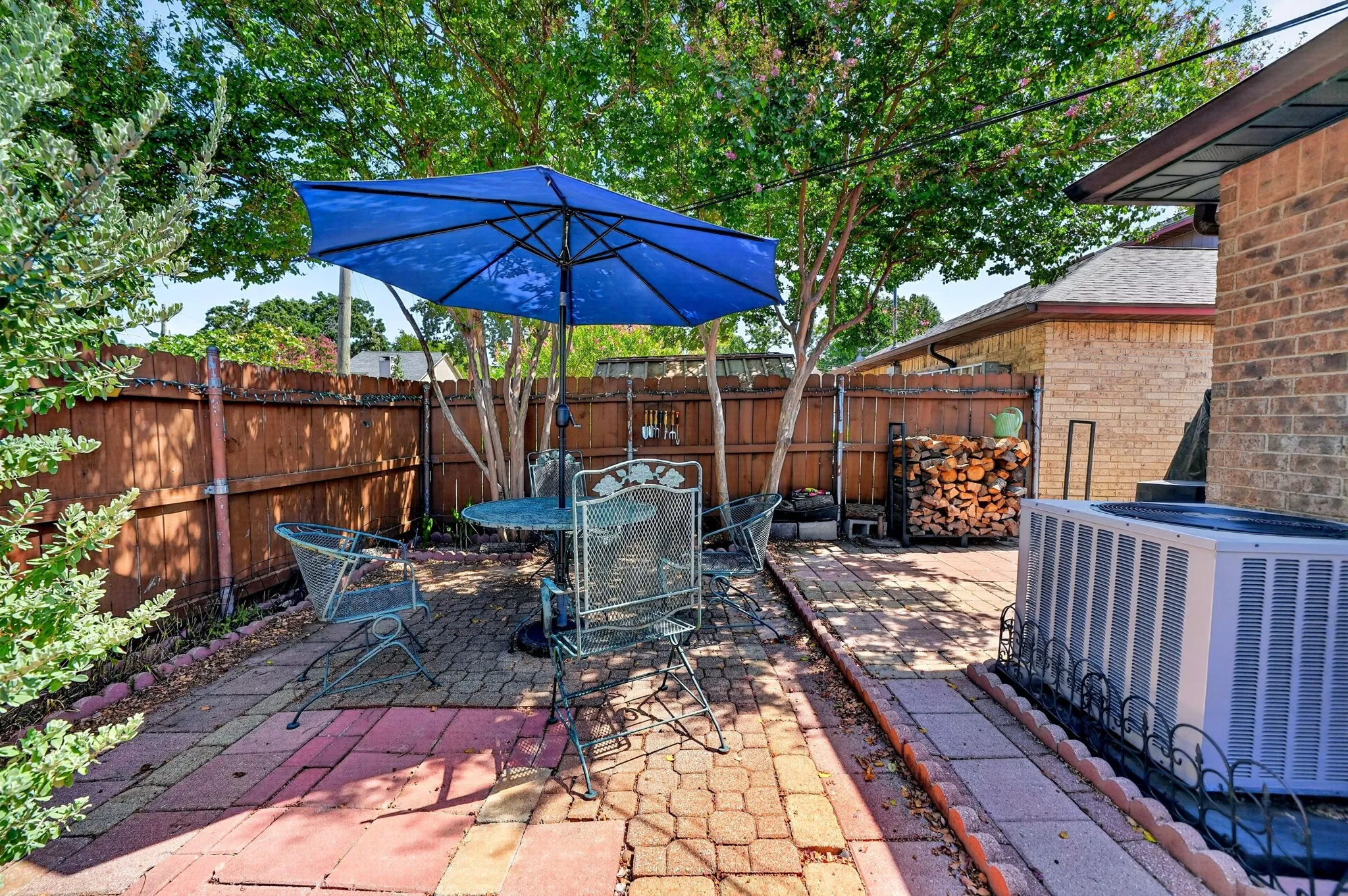 Brick patio with mature trees and a wood fence