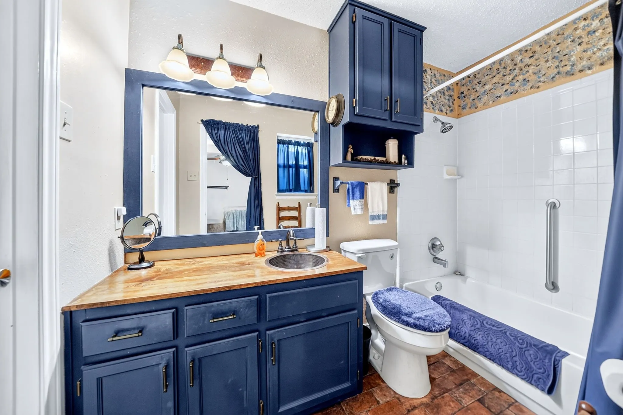 Bathroom featuring a built-in vanity with wood-finish countertop, undermount sink, and dark blue cabinetry