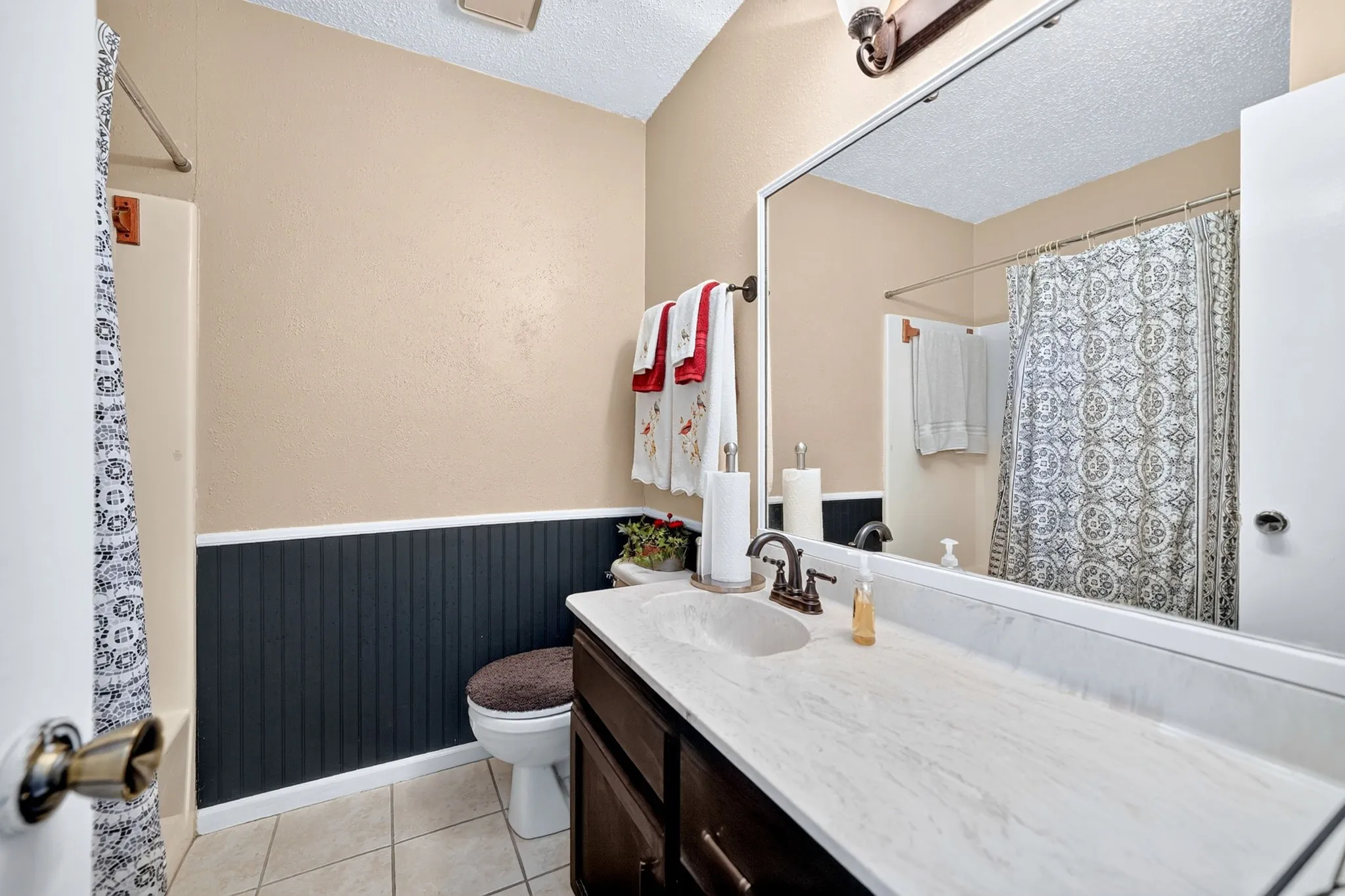Bathroom featuring a single vanity with an integrated sink, dark wood-finish cabinetry, and a large wall-mounted mirror