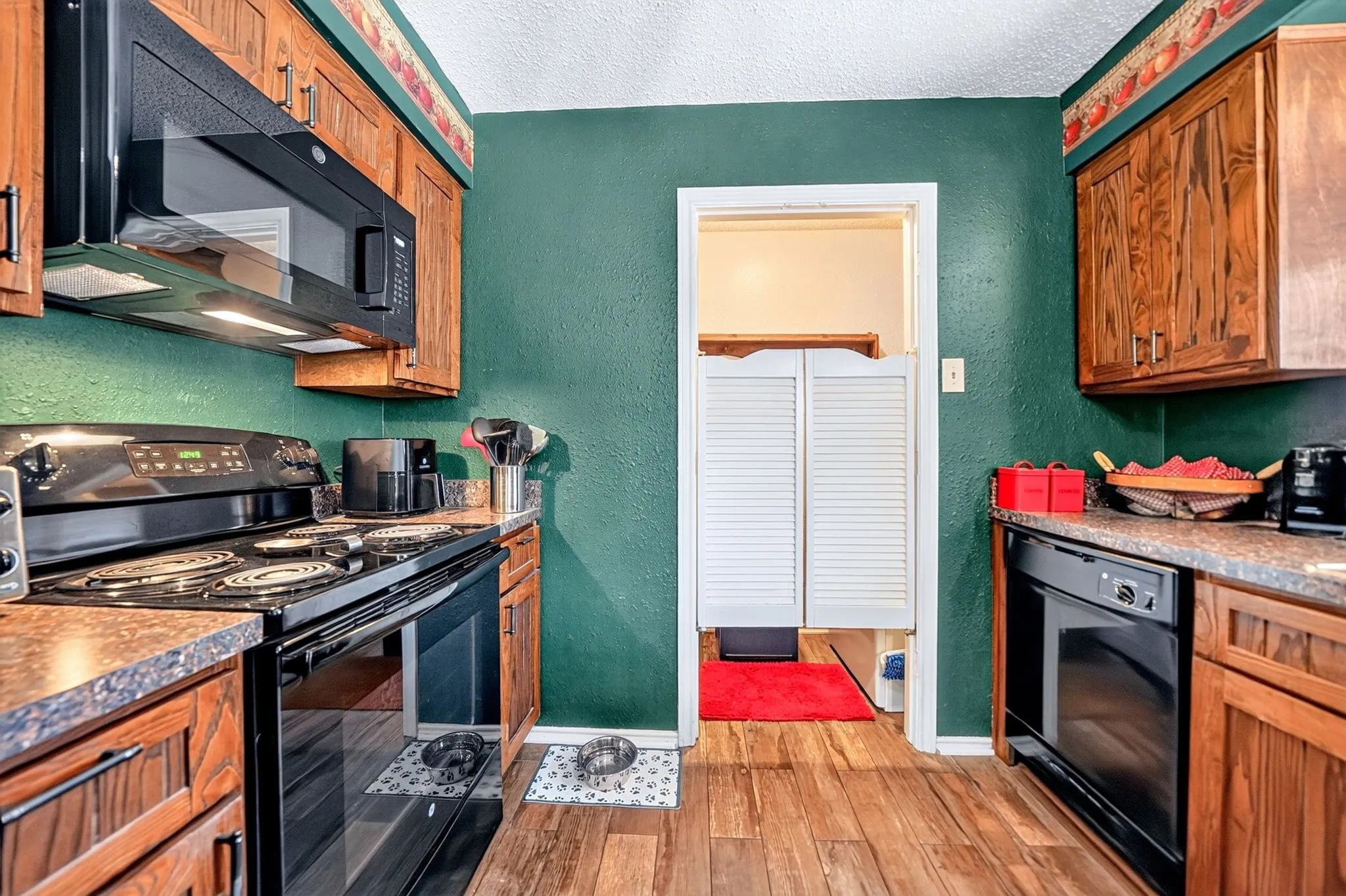 Wood-finish flooring with a black electric range and built-in microwave