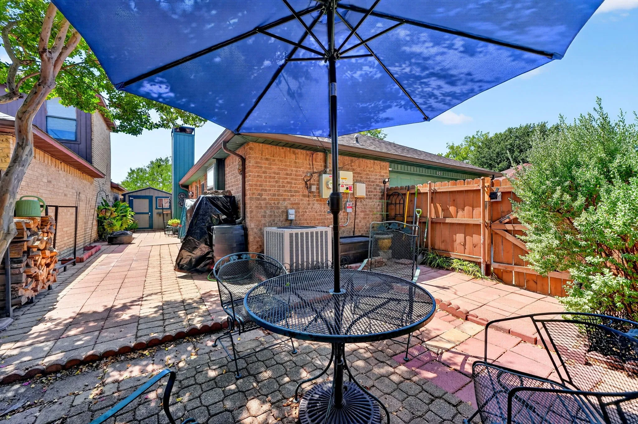 Brick exterior, paved patio, wood fencing, and mature landscaping
