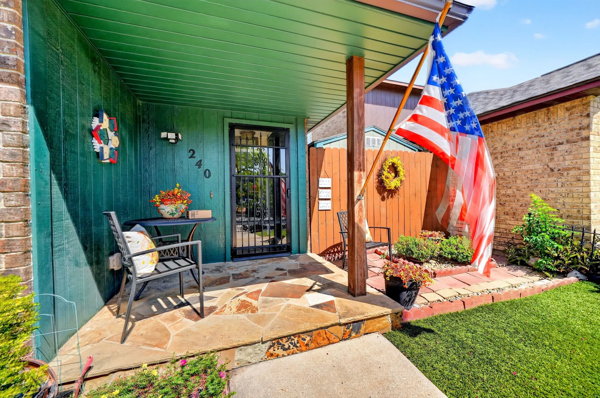 Flagstone patio with a covered entry, wood siding, and a security screen door