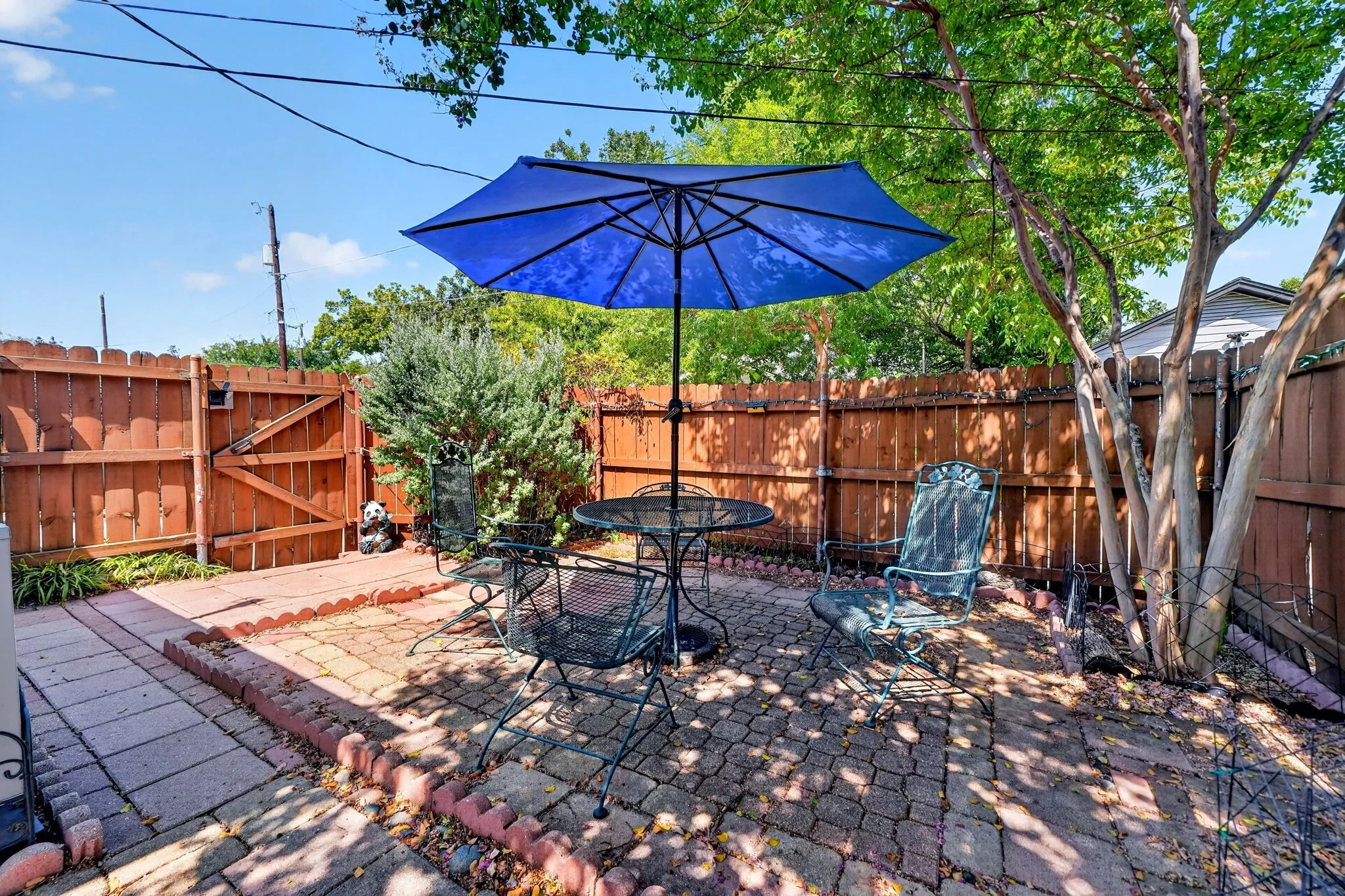 Private outdoor patio featuring brick paver flooring, a wood privacy fence, and mature landscaping