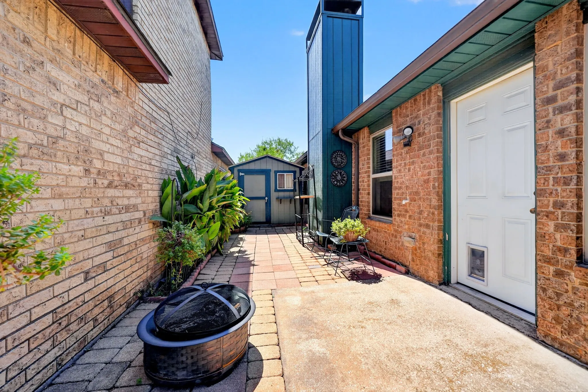 Brick exterior, wood siding on chimney, paved walkway, storage shed, exterior entry door