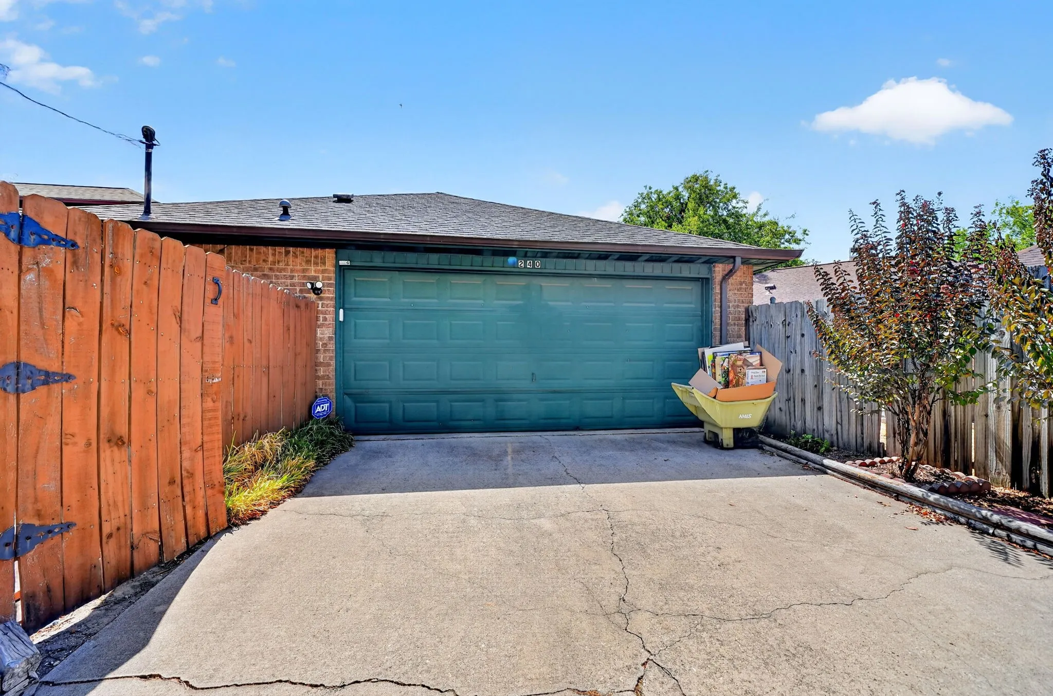 Attached garage with a teal door, concrete driveway, and brick exterior