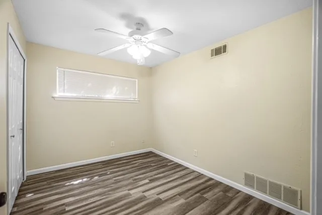 Wood-finish flooring, ceiling fan with integrated lighting, horizontal window with blinds, and bi-fold closet door