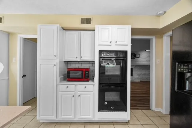 White cabinetry, built-in double oven, tile flooring, subway tile backsplash, and a built-in refrigerator