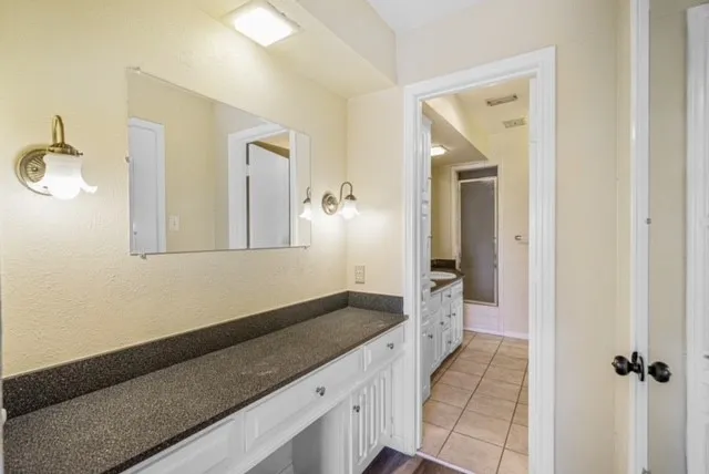 Integrated vanity with a dark countertop and white cabinetry, complemented by wall sconces