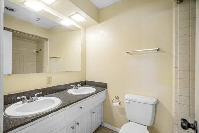 Dual vanity with integrated sinks, dark stone-finish countertop, full-width mirror, and overhead lighting