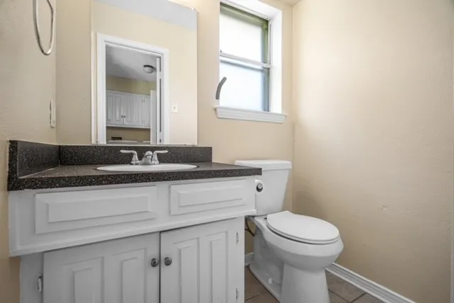Vanity with white cabinetry, dark speckled countertop, and integrated sink