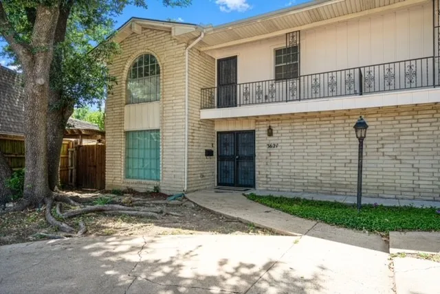 Brick facade, arched window, wrought iron balcony, front entry security doors, and exterior lantern fixture