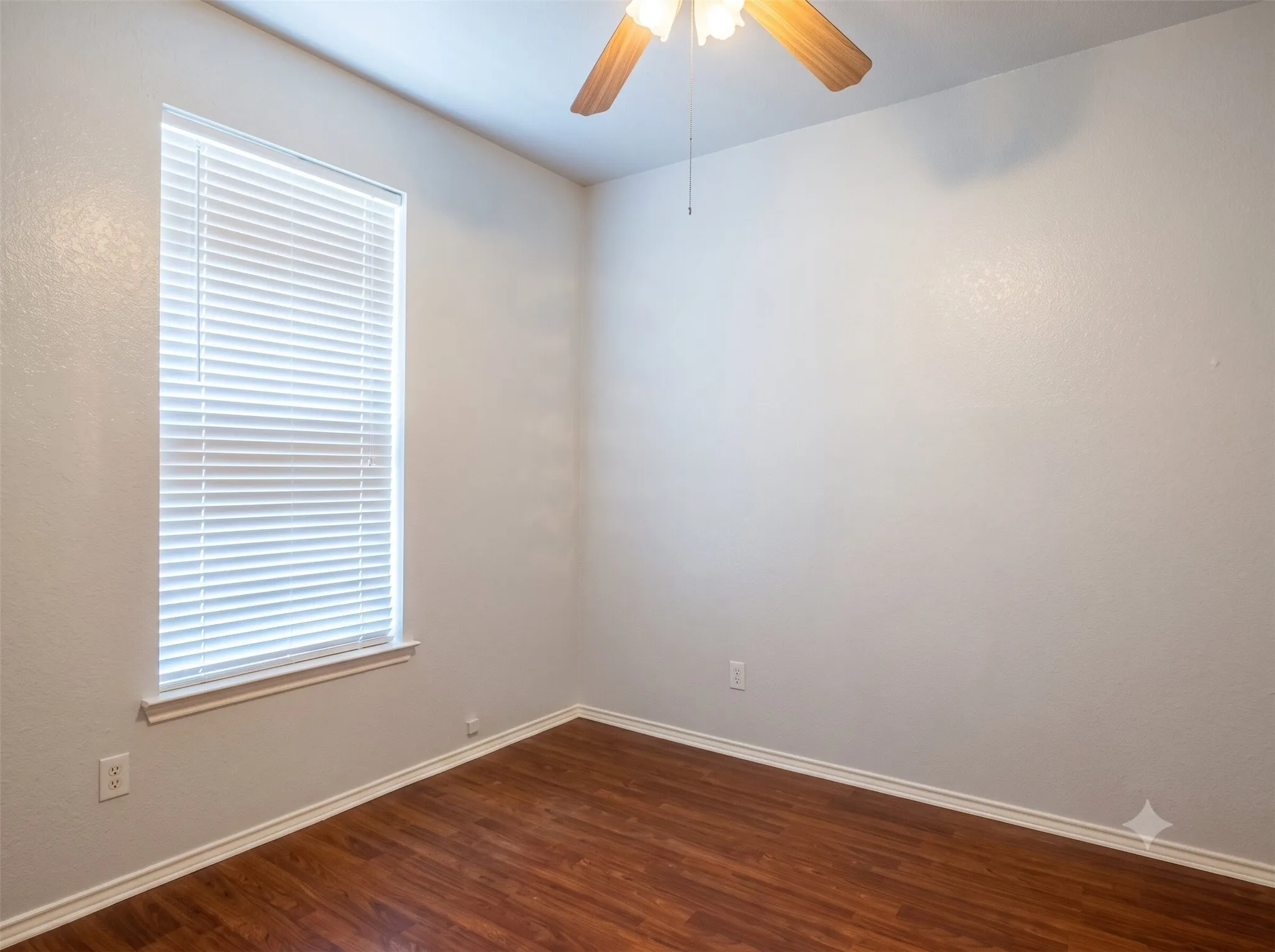 Wood-finish flooring, a ceiling fan with light fixture, and a window with blinds