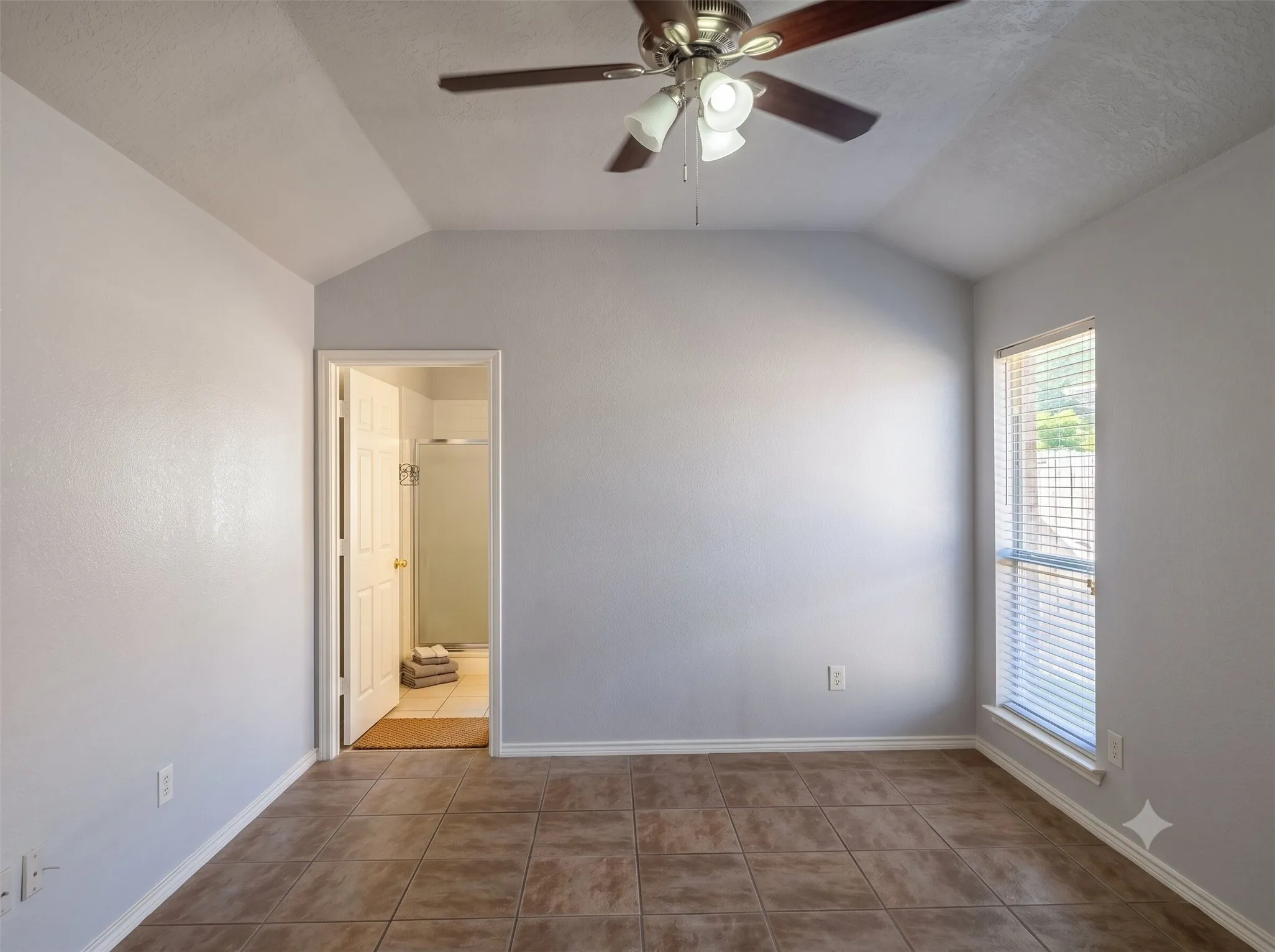 Vaulted ceiling bedroom with tile flooring and a ceiling fan