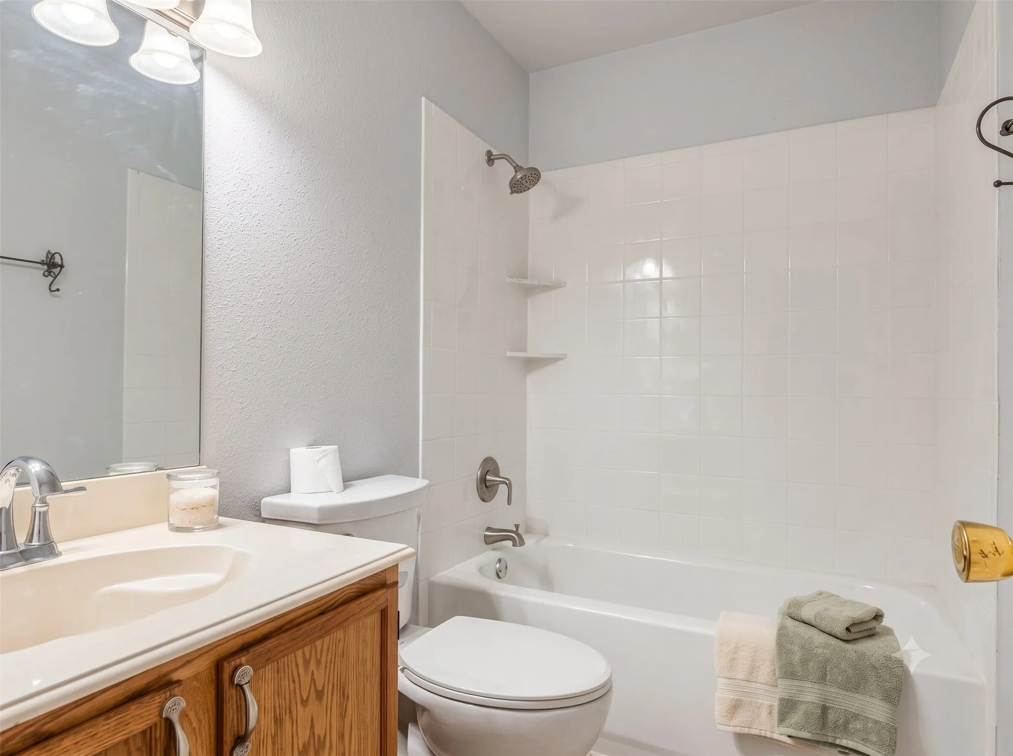 Bathroom featuring a white subway tile shower surround, a built-in bathtub, and a wood-finish vanity with an integrated sink