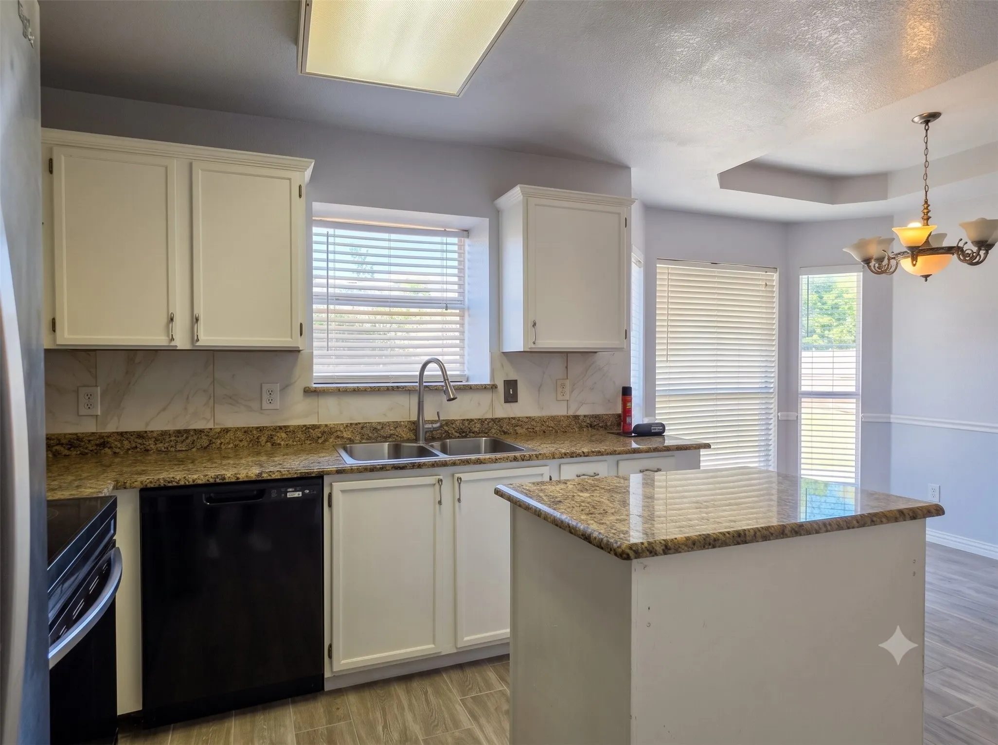 Kitchen featuring white cabinetry, granite-style countertops, stainless steel sink, and wood-finish flooring