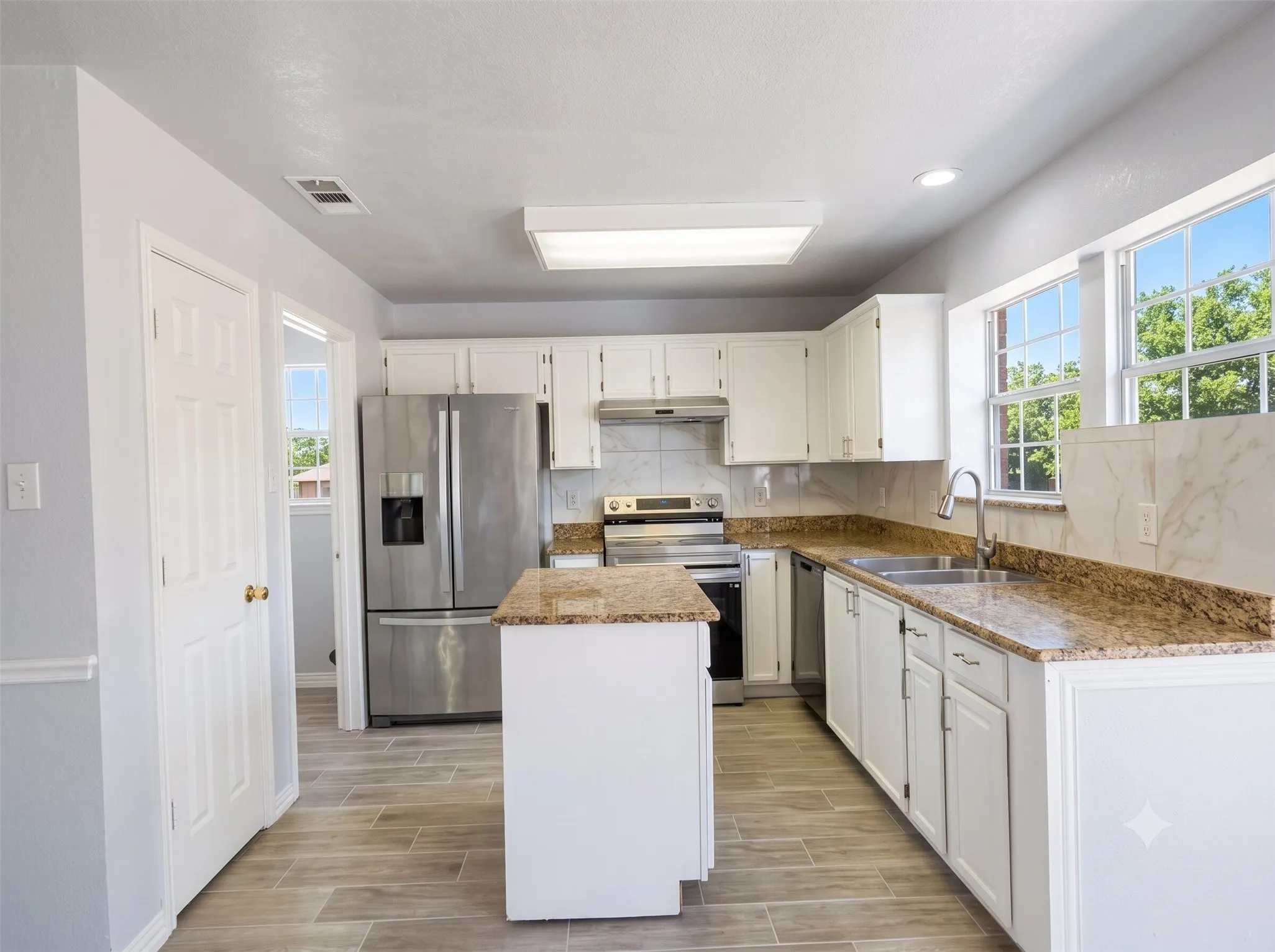 Kitchen featuring white cabinetry, stainless steel appliances, granite countertops, and wood-finish flooring