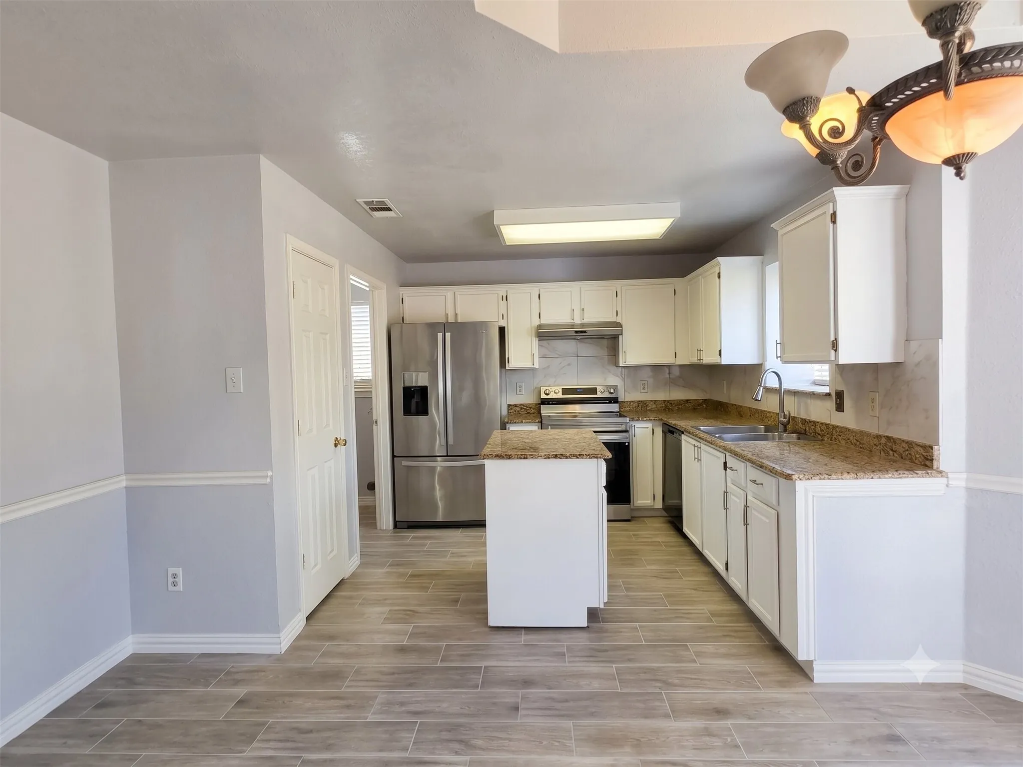Kitchen featuring white cabinetry, stainless steel appliances, a center island, and wood-finish flooring