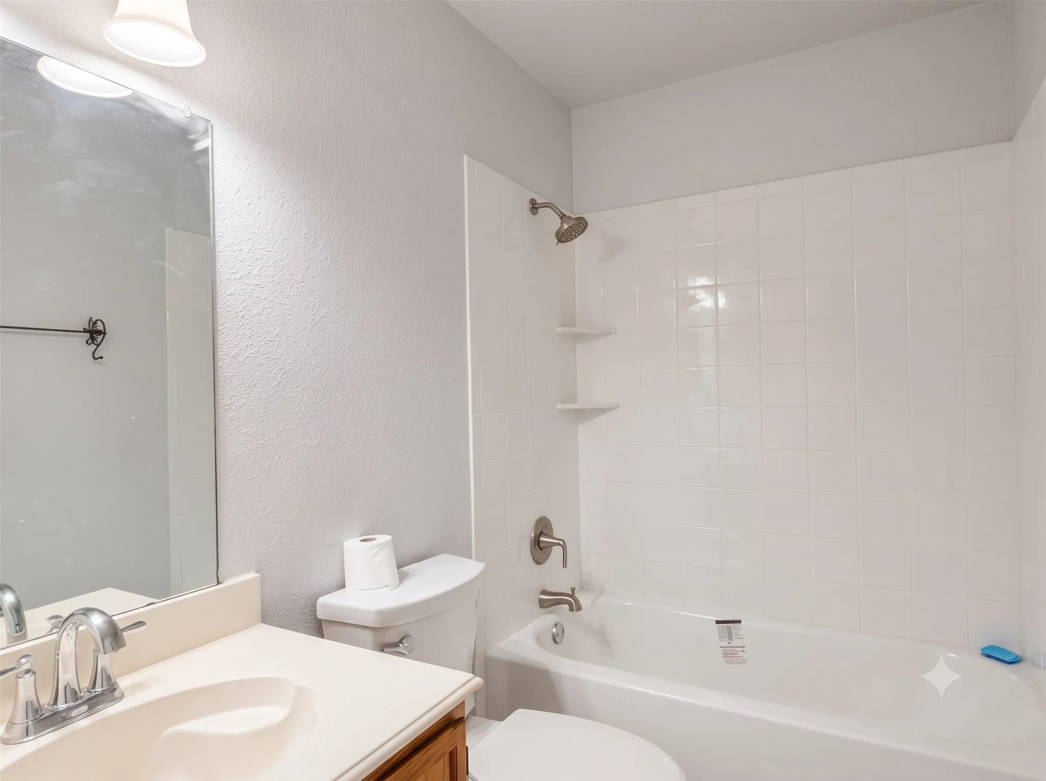 Bathroom featuring a vanity with an integrated sink, a rectangular mirror, and a bathtub with white subway tile surround and integrated shelving