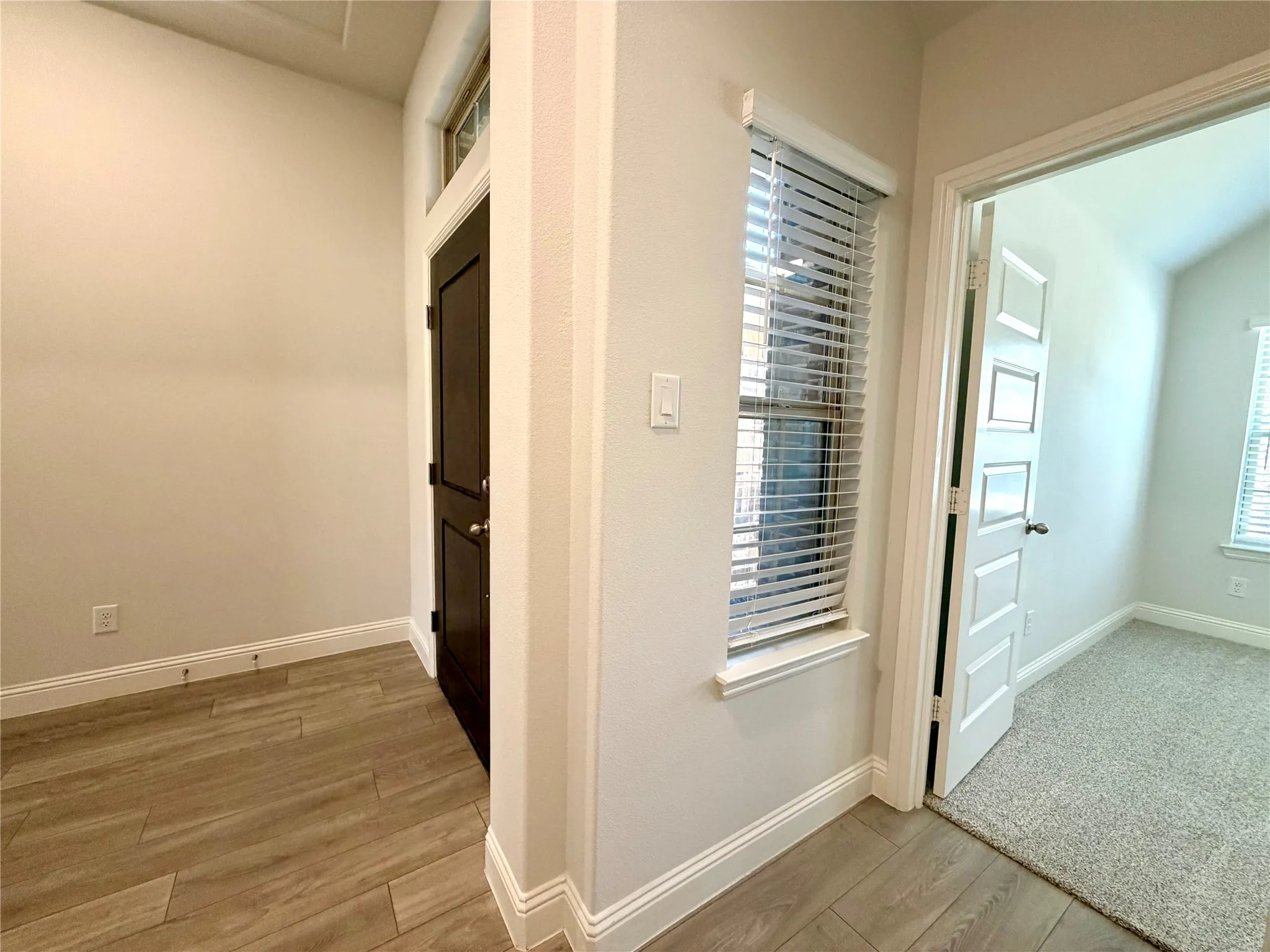 Bright, natural light floods the entryway and front hallway, which features a charming transom window above the front door and an additional window looking out toward the entry porch. This bright, inviting hallway leads directly into a convenient front bedroom.