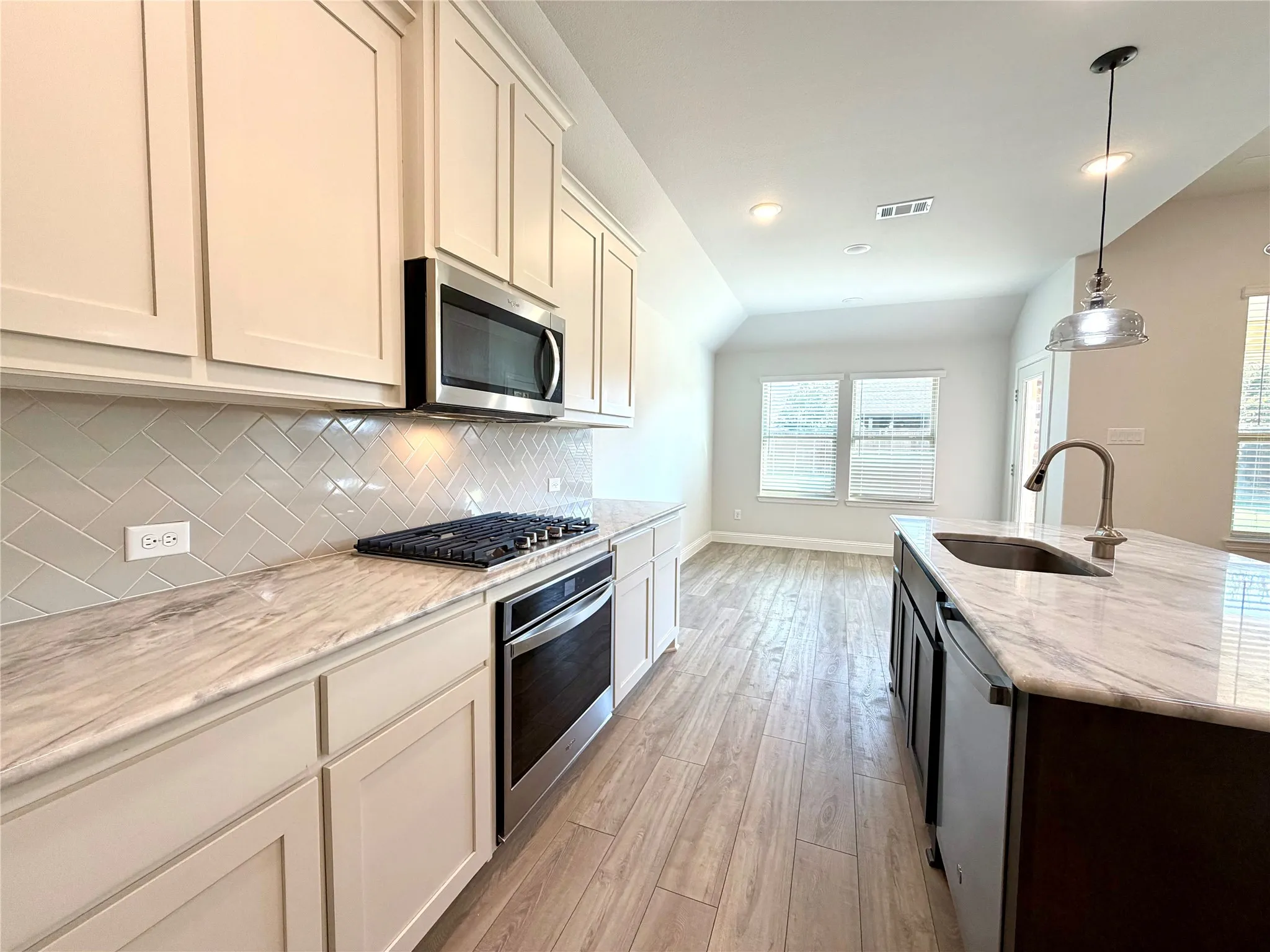This bright and airy kitchen is designed with an open-concept layout, featuring expansive quartz counter space that is perfect for meal preparation, stainless steel appliances, and a seamless, natural flow into the dining area, making it an ideal space for both daily living and hosting dinner gatherings.