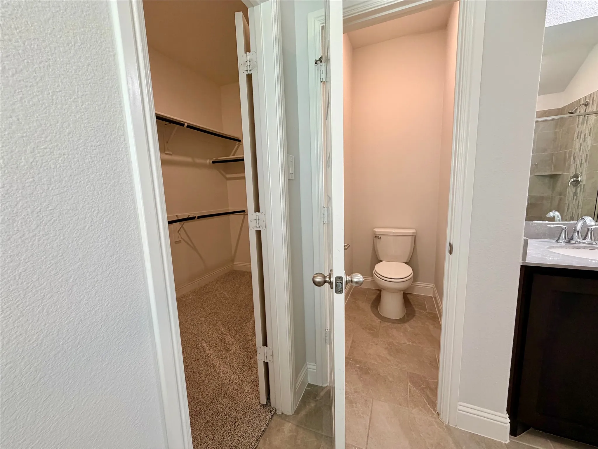 This bathroom features a private, enclosed water closet area that is completely separated from the primary vanity and shower space for enhanced privacy and functionality.