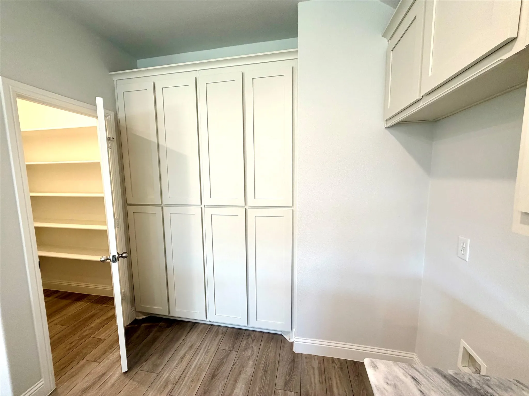 This kitchen features an incredible amount of storage space throughout, highlighted by elegant floor-to-ceiling cabinetry that maximizes vertical utility and a dedicated pantry equipped with custom-designed built-in shelving for seamless organization and convenience.