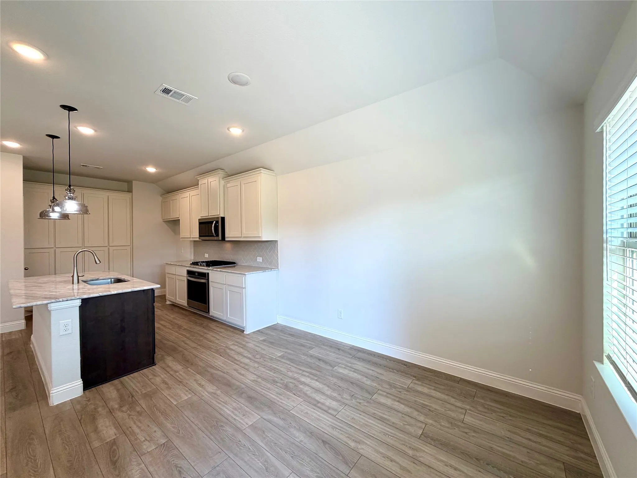 This photo captures spacious dining room, showcasing a beautiful view that extends seamlessly through the space toward the kitchen, highlighting the open-concept layout and natural flow of the home.