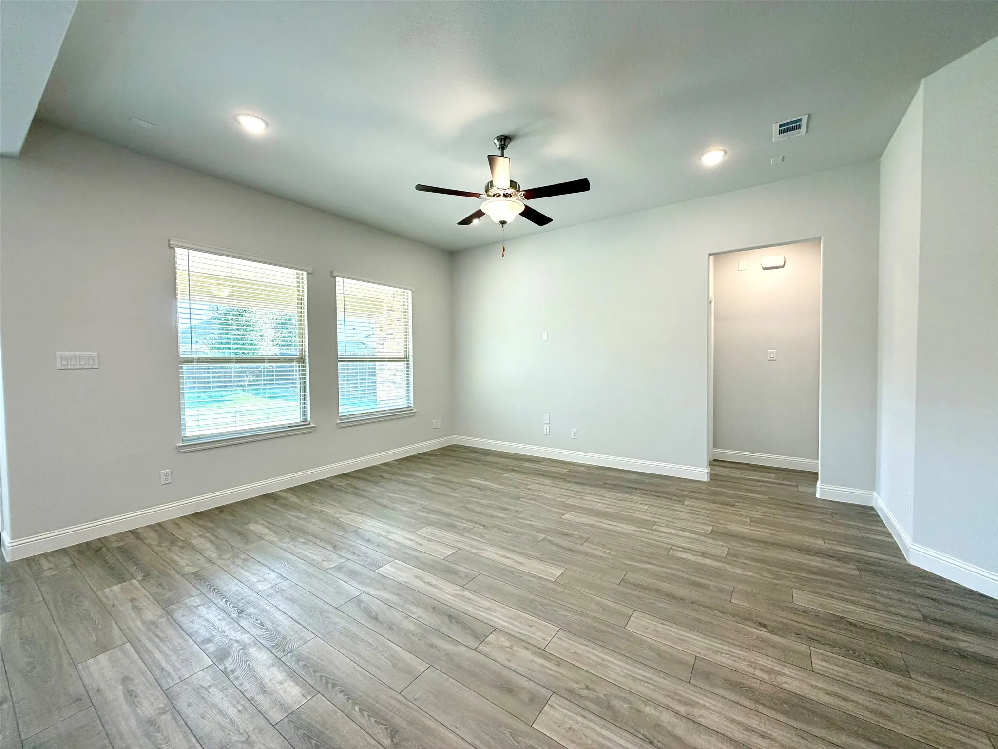 This spacious living area features impressive high ceilings that create an open, airy atmosphere. View looking at hallway to the primary bedroom suite.