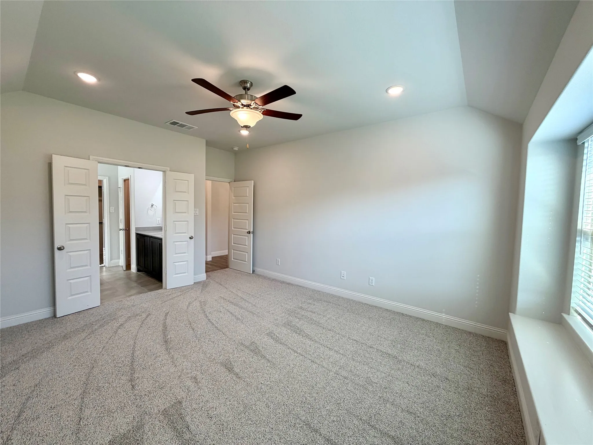 Another view of the the spacious and well-appointed primary bedroom suite, highlighting the elegant design, natural lighting, and overall comfortable layout of the room.
