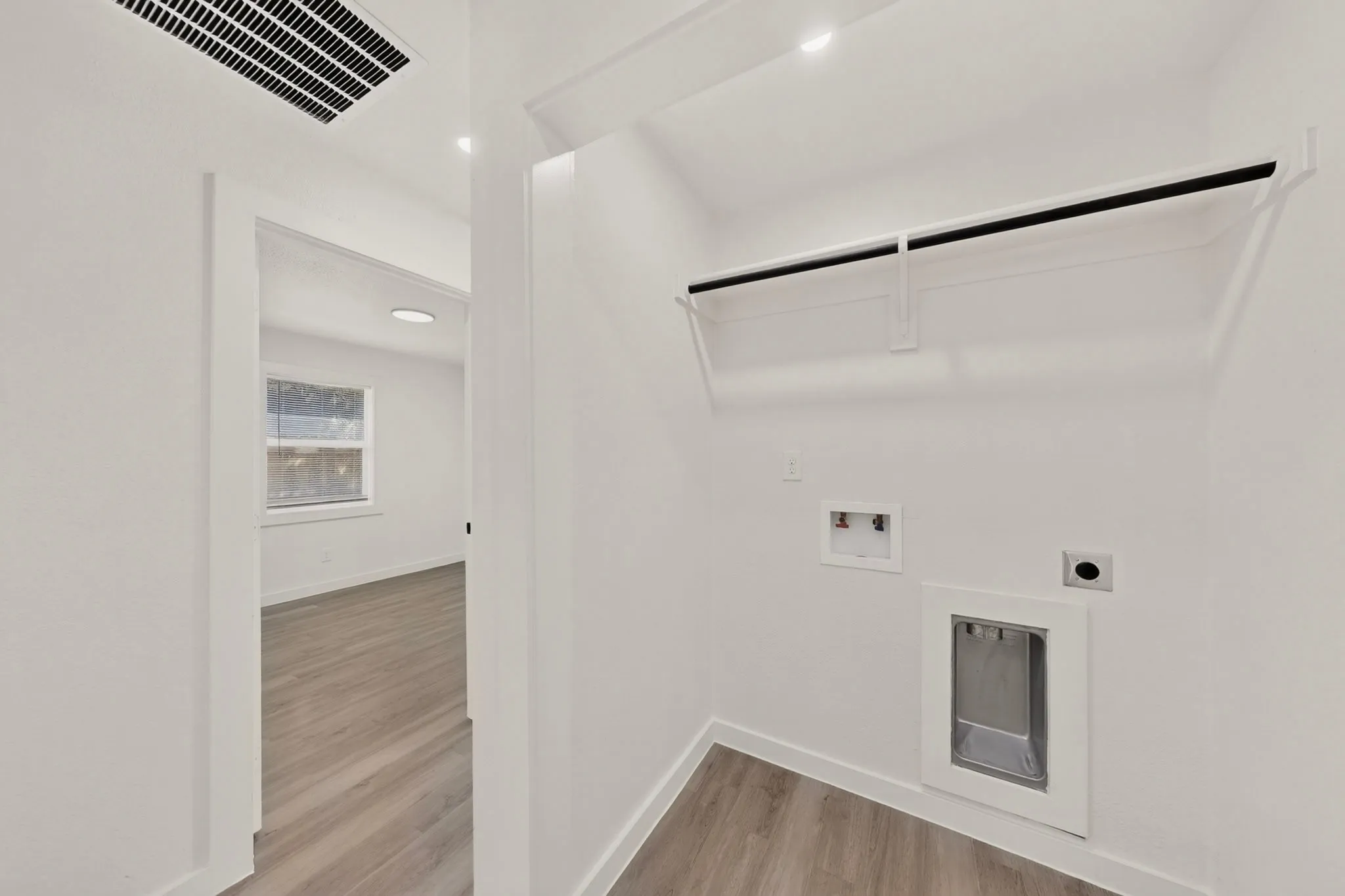 Utility closet with wood-finish flooring, white walls, built-in shelving, and washer/dryer hookups