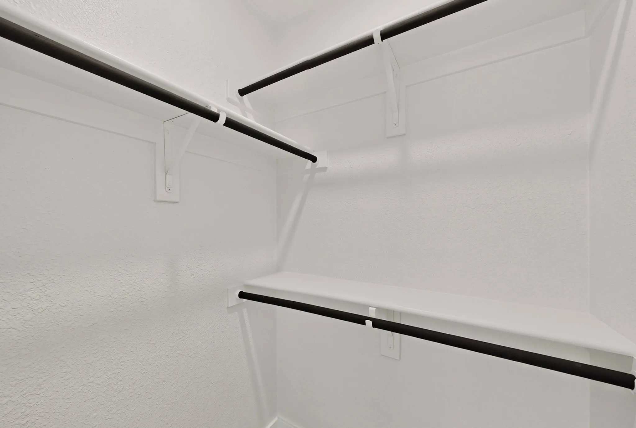 Built-in closet shelving system with white finish and dark-finished hanging rods