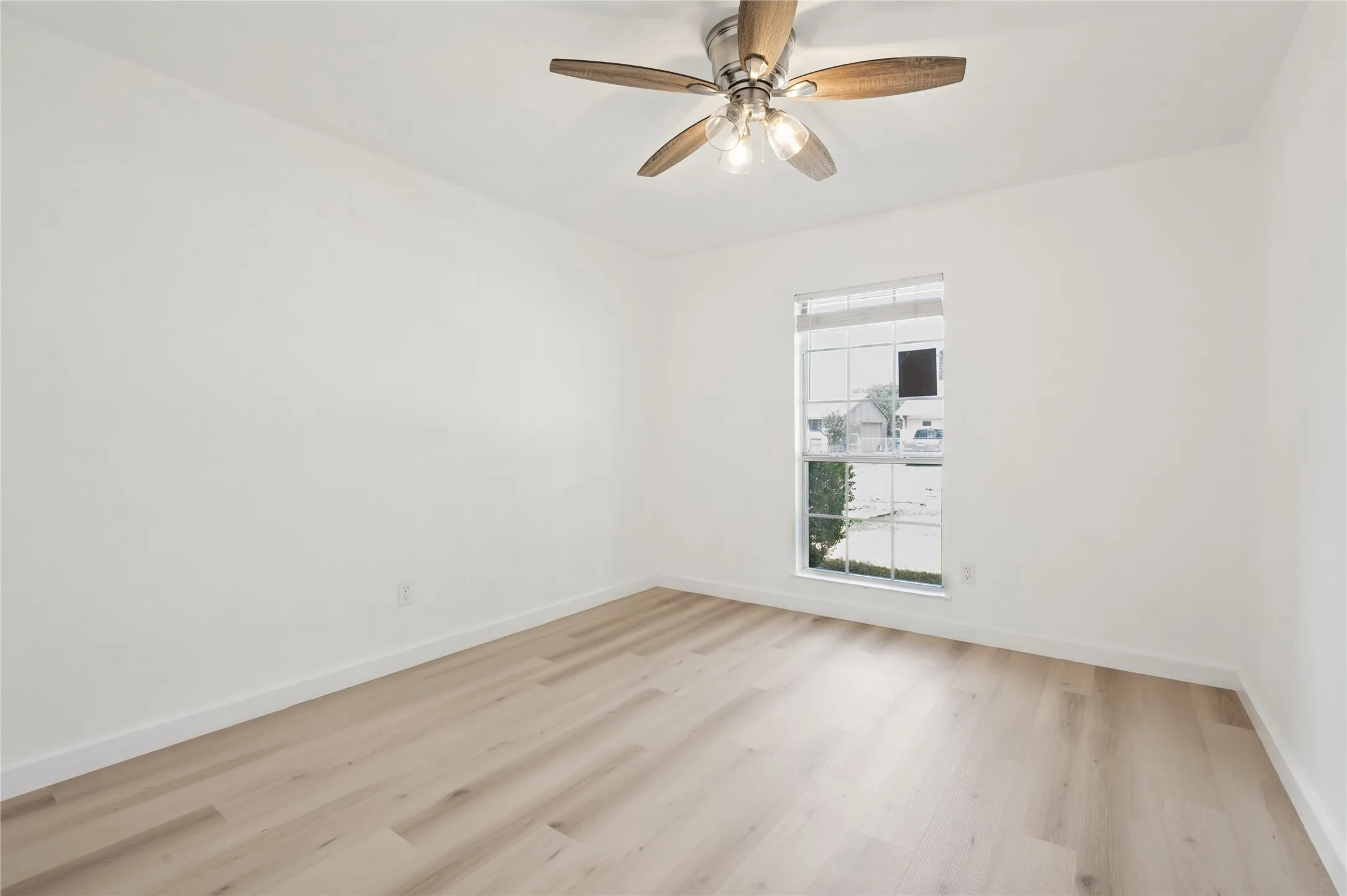 Recessed window with white blinds, neutral wall paint, wood-finish flooring, and a ceiling fan with integrated lighting