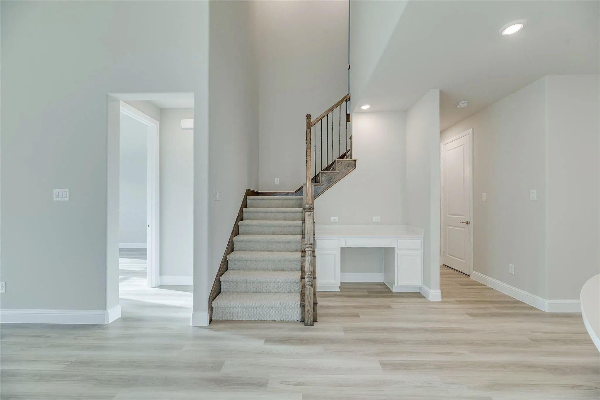 Two-story foyer with wood-finish flooring, recessed lighting, and a built-in desk