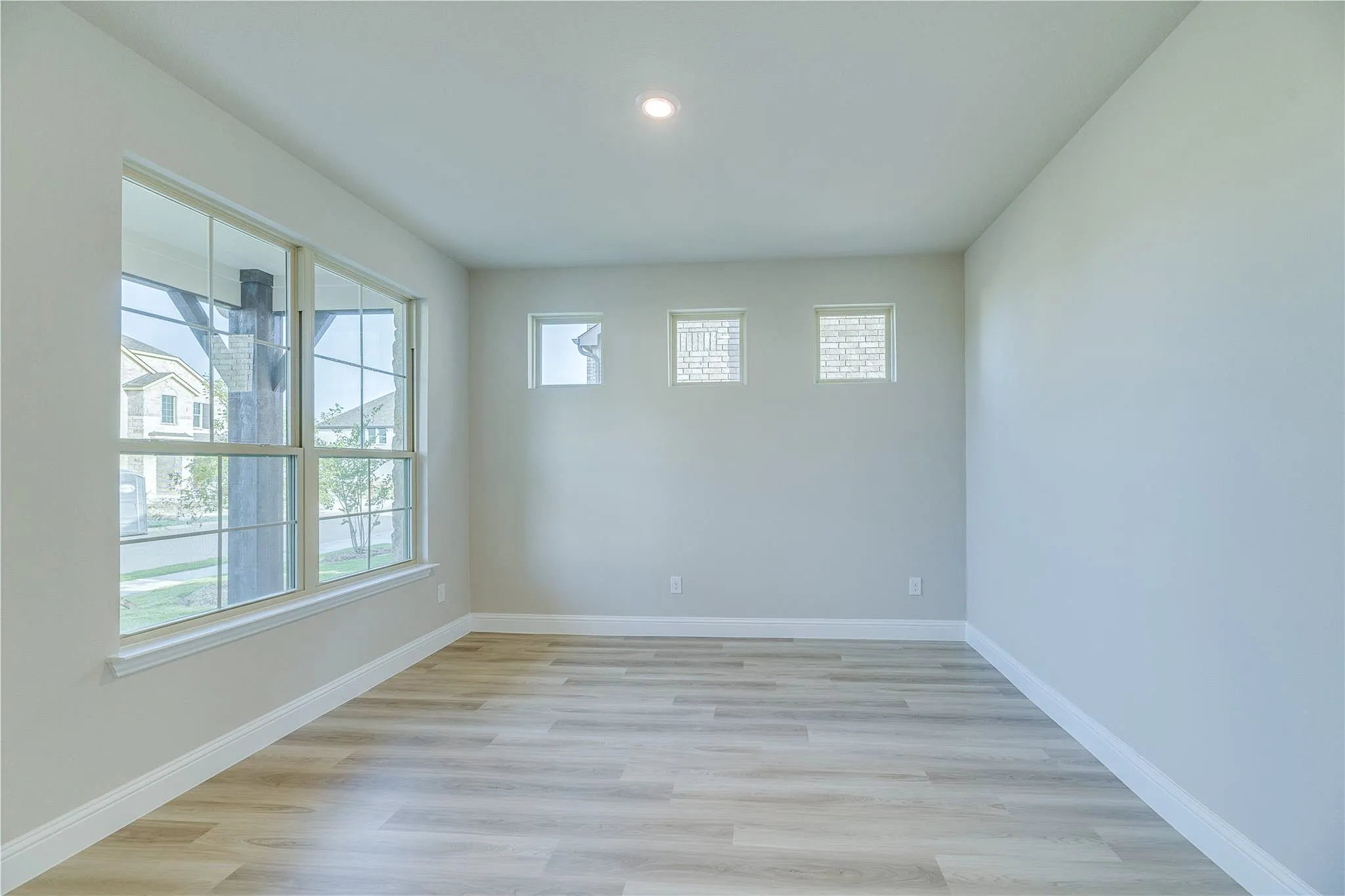 Neutral wall finish, recessed lighting, wood-finish flooring, multiple windows, and a high ceiling