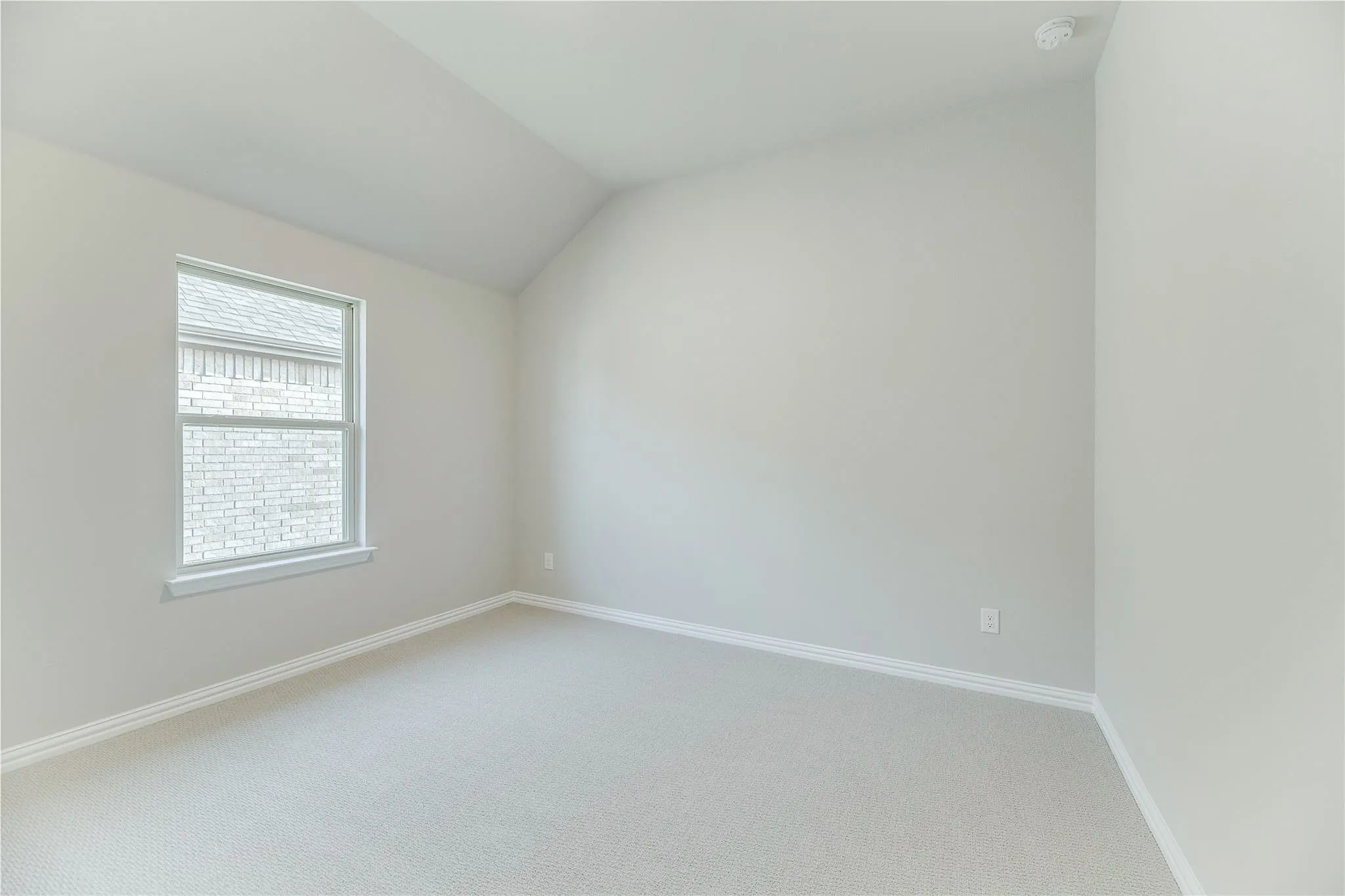Vaulted ceiling, light-toned carpeting, and a double-pane window with white trim