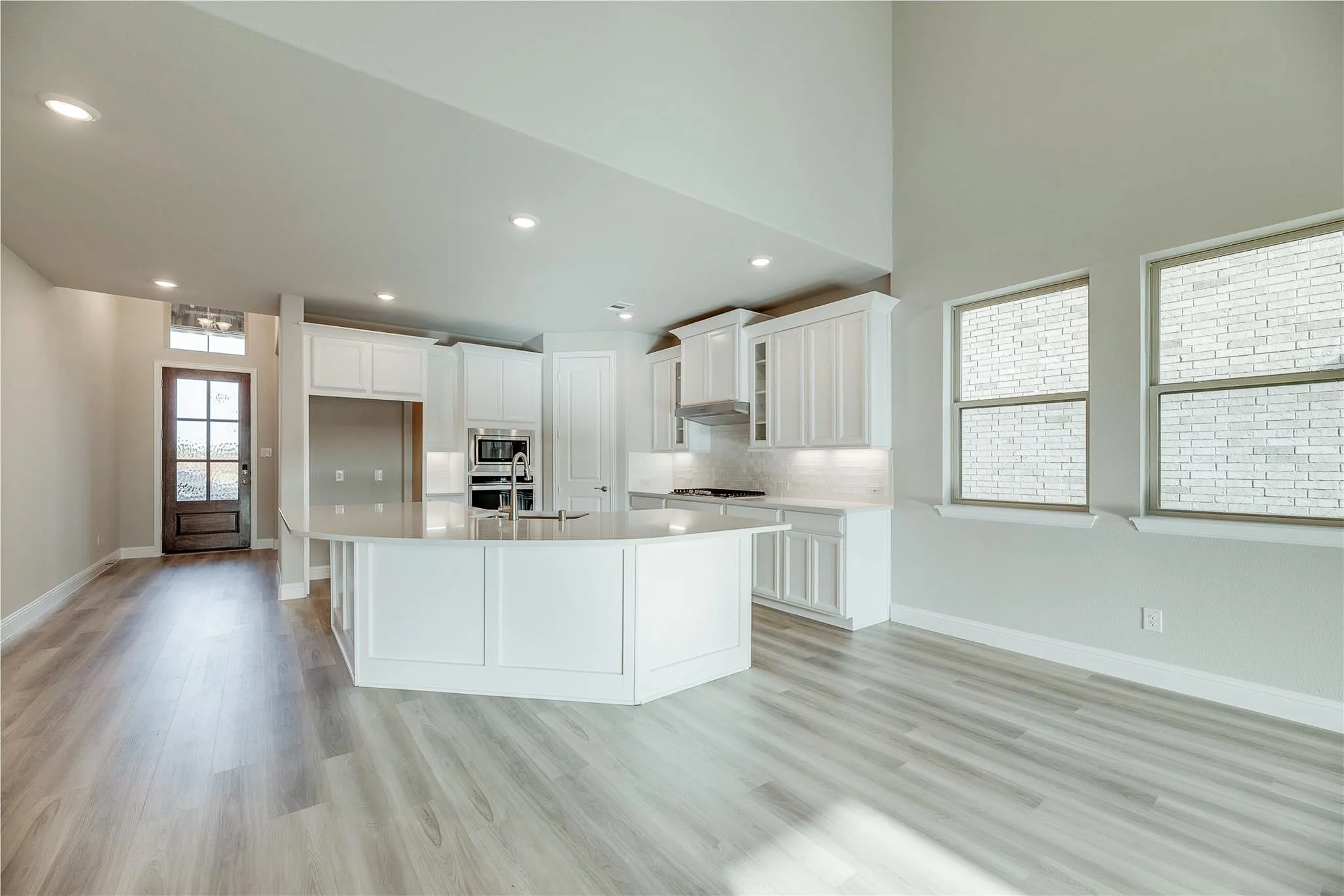 Open-concept living space with wood-finish flooring, a two-story ceiling, and a kitchen island with seating