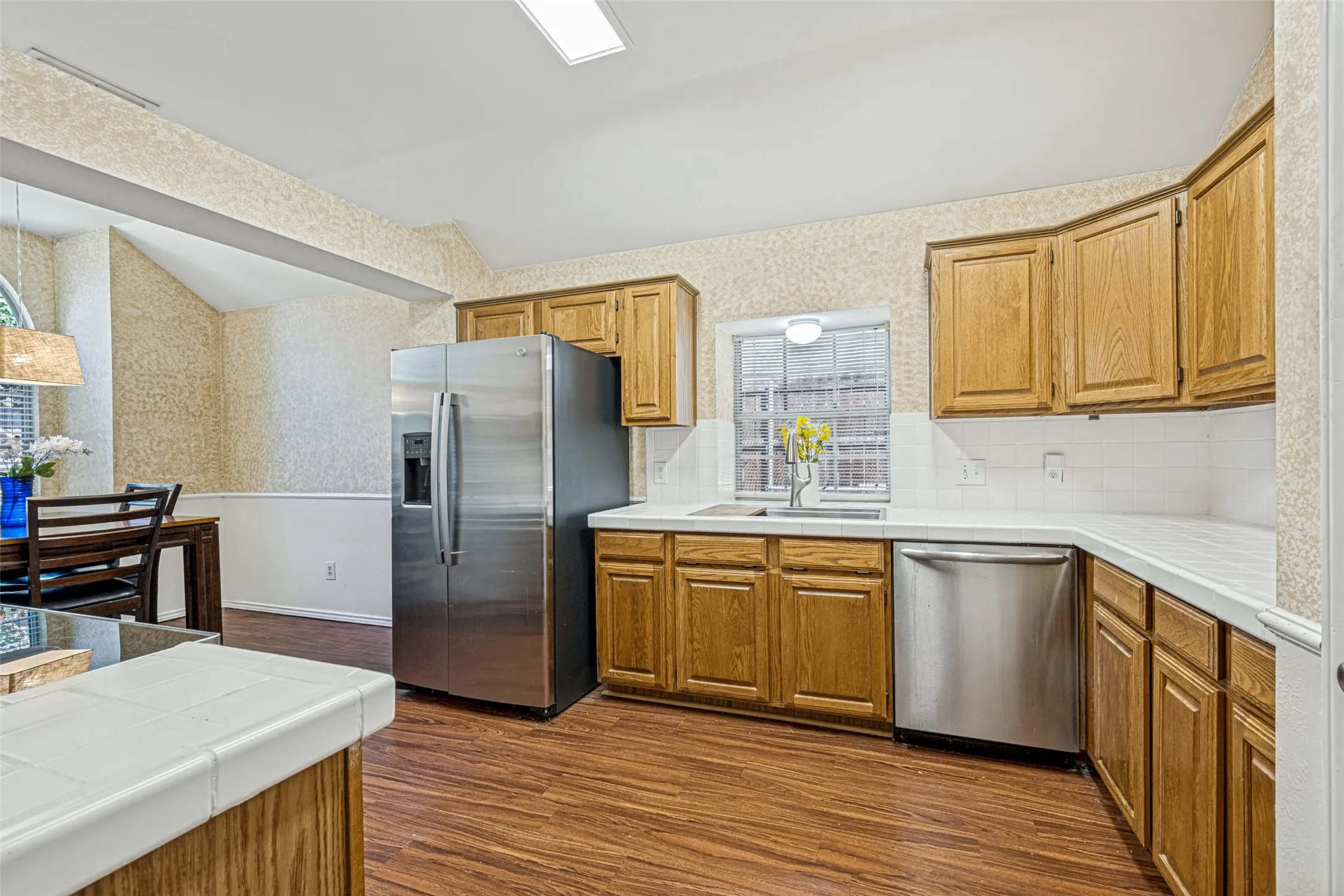 Kitchen featuring wood-finish flooring, wood cabinetry, white countertops, and a white subway tile backsplash