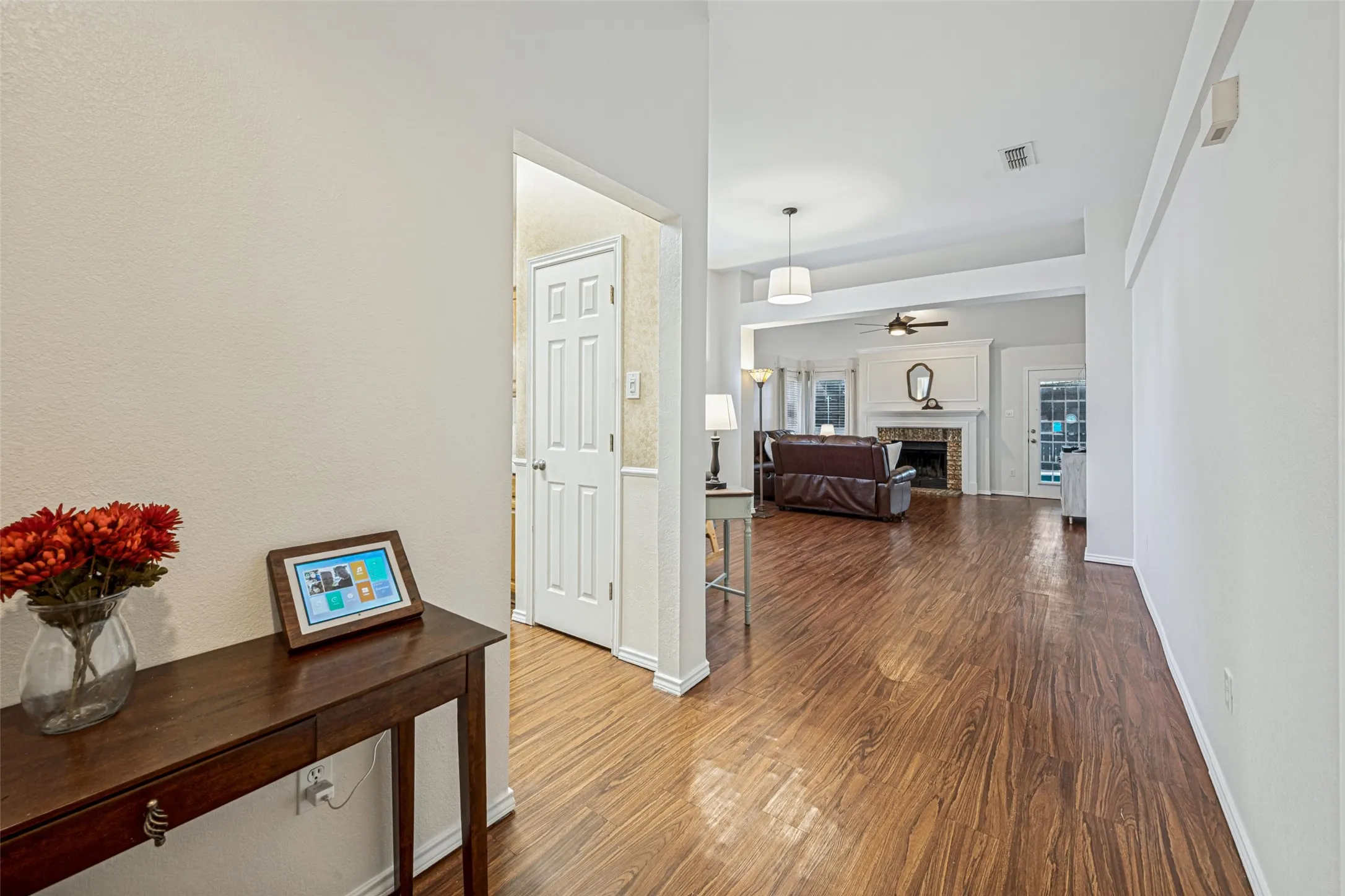 Wood-finish flooring throughout, fireplace with a mantle, and white trim