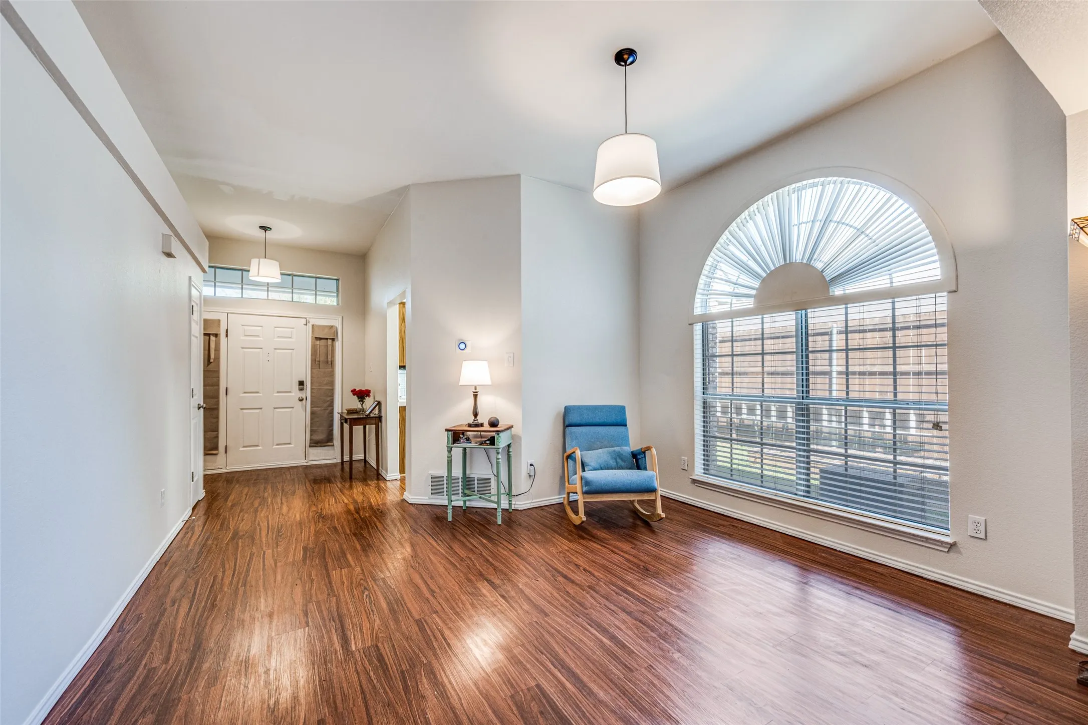 Soaring vaulted ceiling, wood-finish flooring, and an arched window with blinds