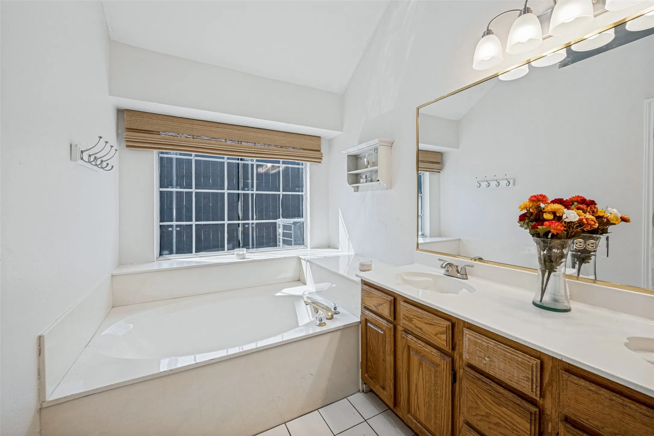 Dual vanity with integrated sinks, wood-finish cabinetry, and a spacious framed mirror