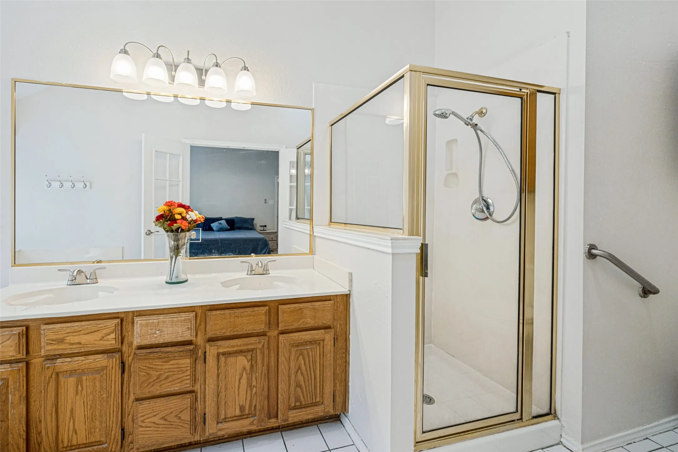 Dual vanity with undermount sinks, wood-finish cabinetry, and a large wall-mounted mirror